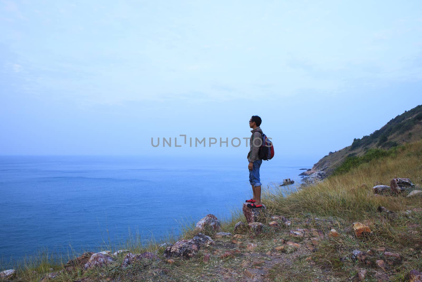 backpack man standing on rock mountain and looking to ocean use  by khunaspix