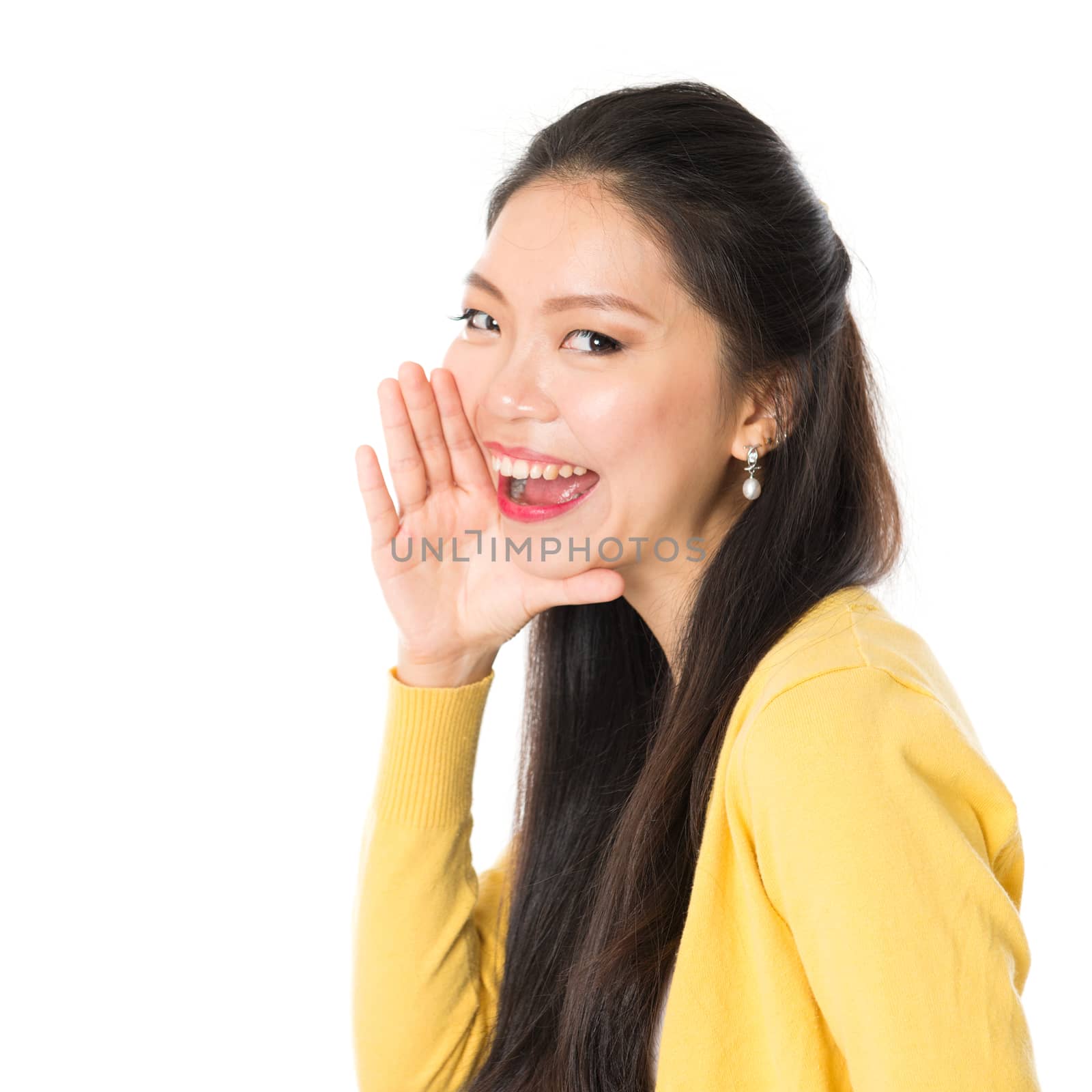 Asian girl shouting and looking at camera, standing isolated on white background.