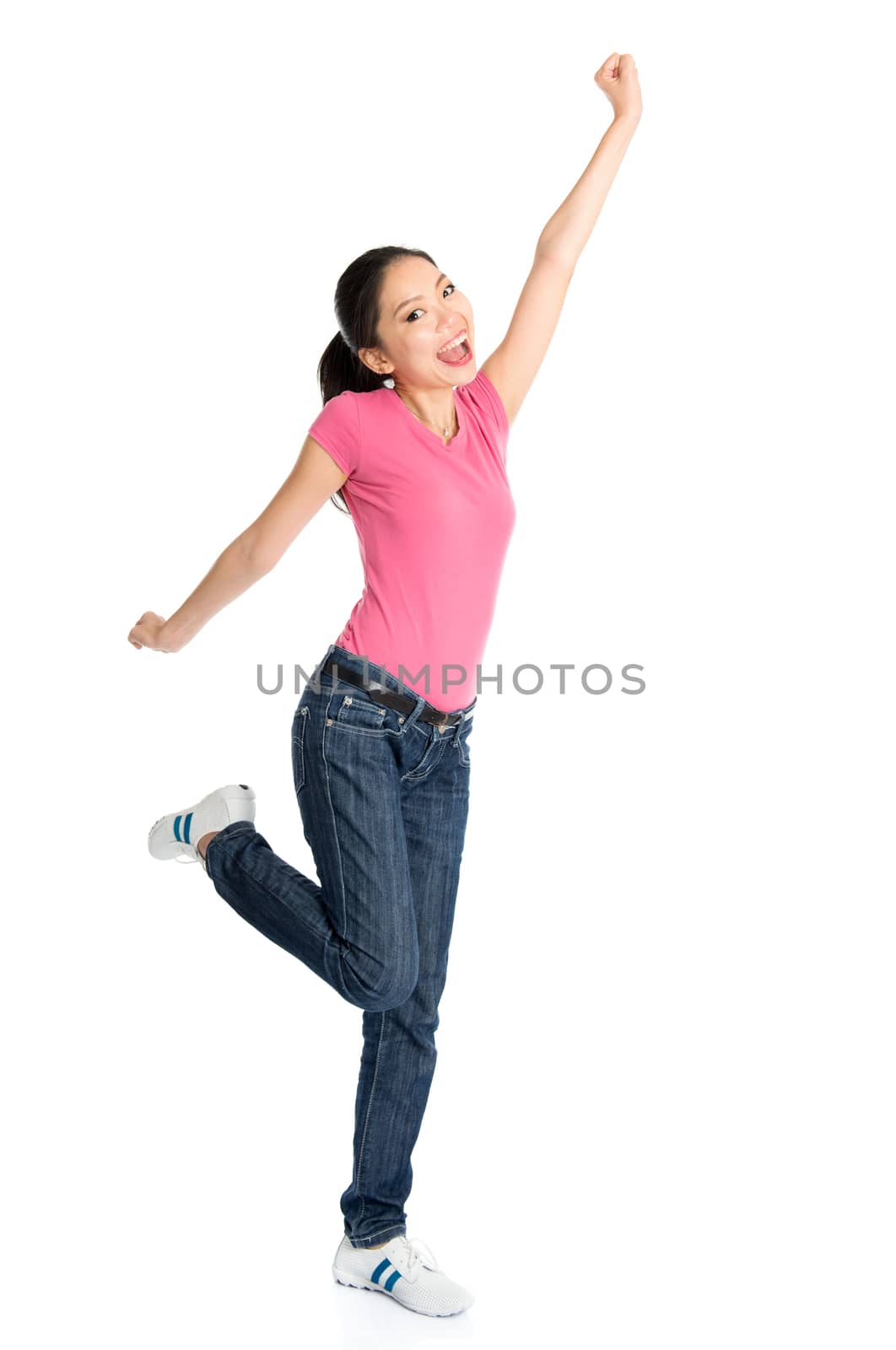 Portrait of young Asian girl in pink shirt and jeans jumping happily, full body standing isolated on white background.