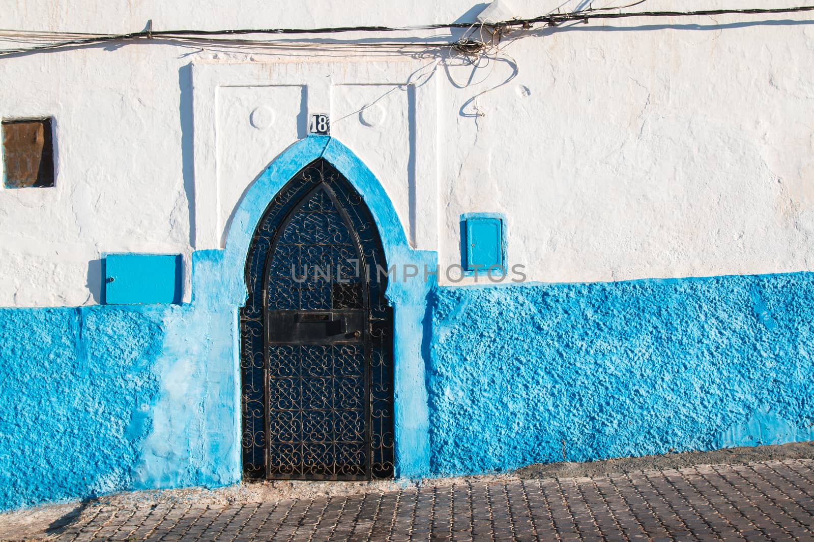 White house with blue detail and a gate, Morocco by YassminPhoto