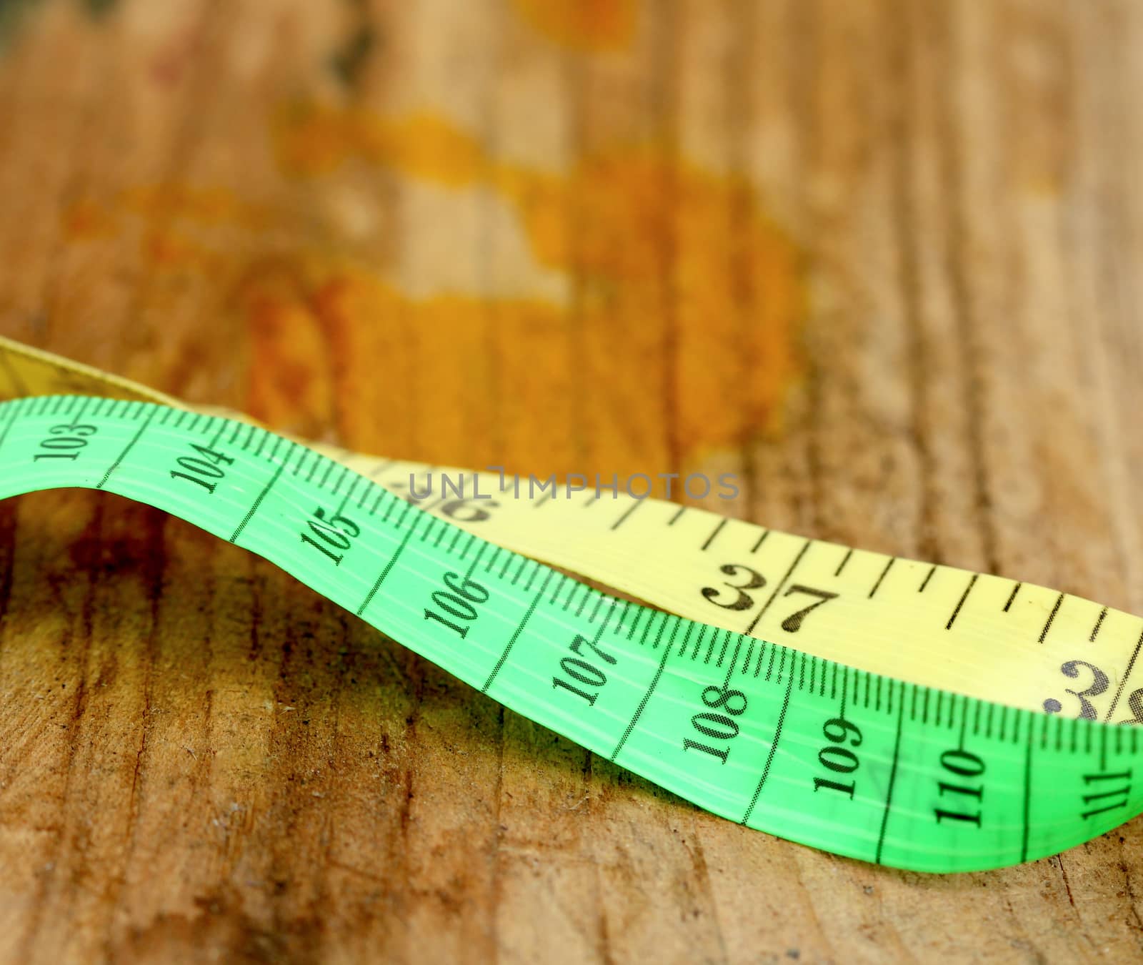 picture of a yellow and green tape measure on wood background