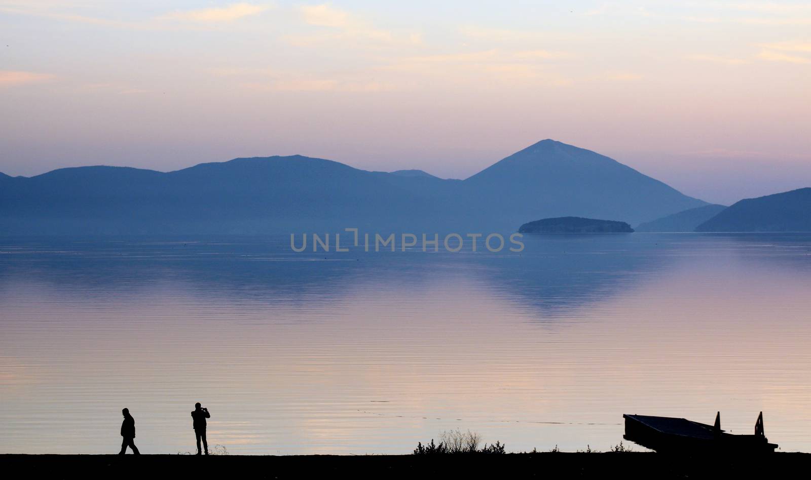 pisture of a men picturing lake prespa in macedonia on sunset
