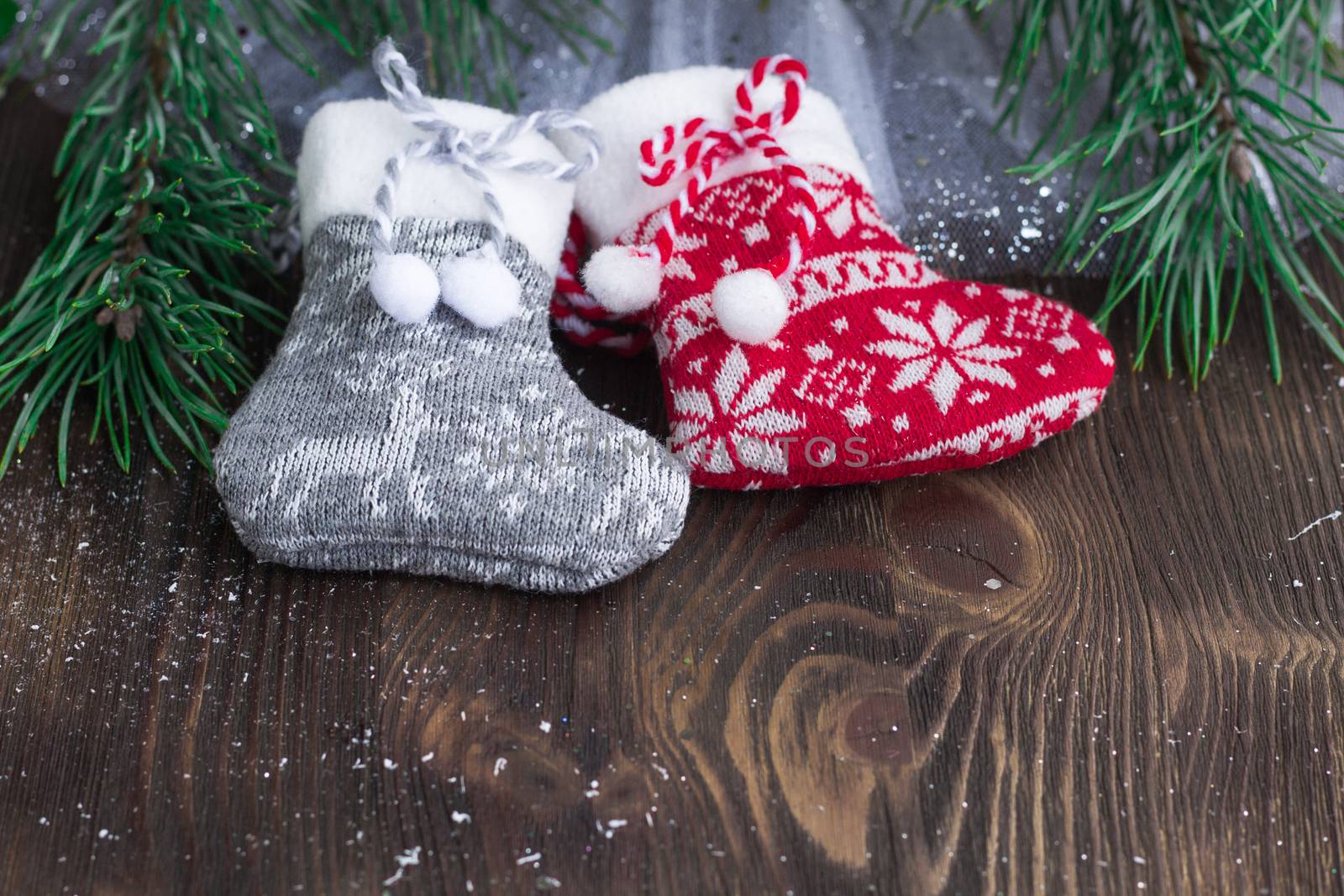 Christmas composition of two knitted socks and xmas tree branches on wooden background
