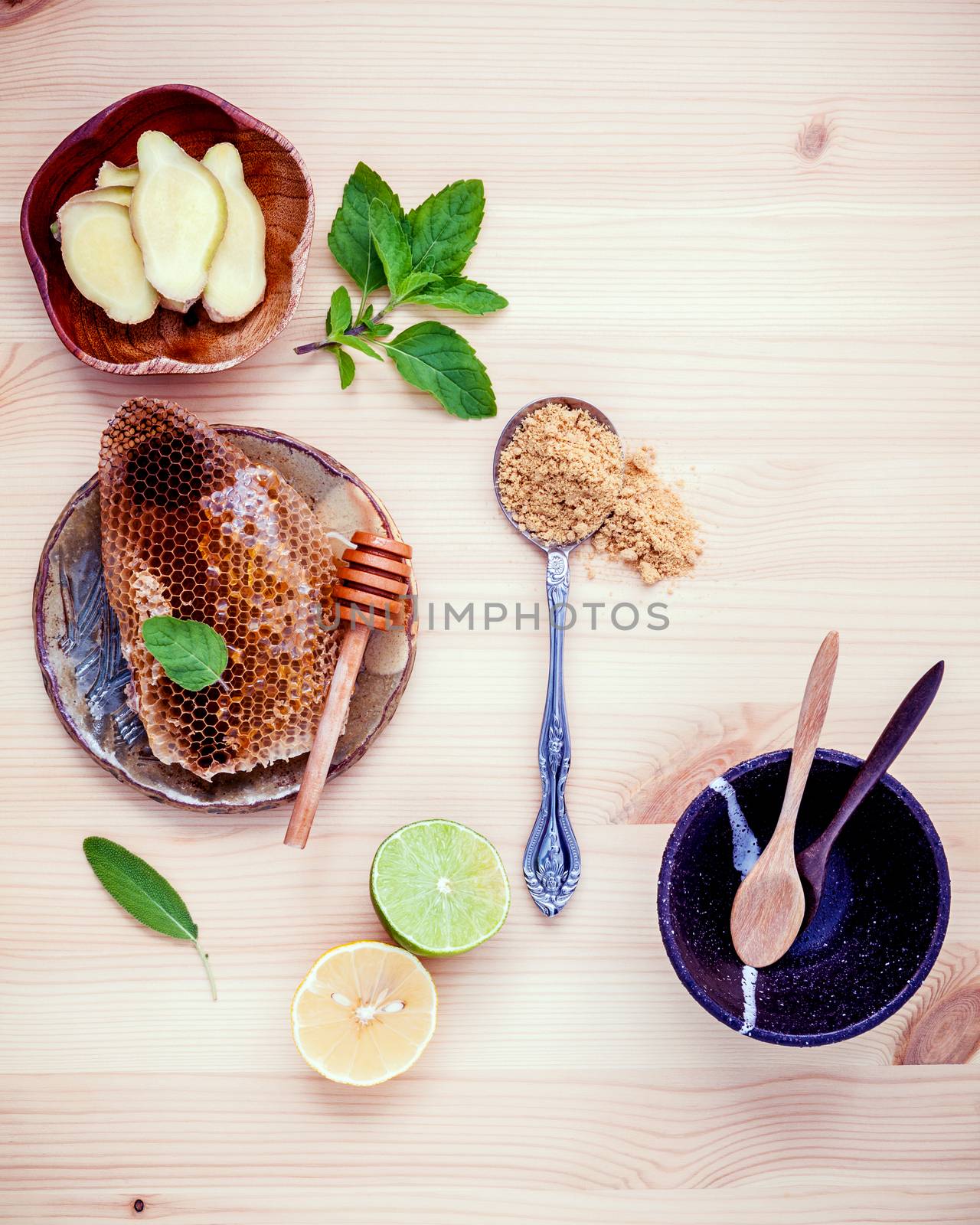 Assortment of dried herbs and fresh herbs tea. Honeycomb in ceramic plate with Fresh herbs peppermint , sage ,lime slice ,ginger powder and ginger root set up on wooden background. 