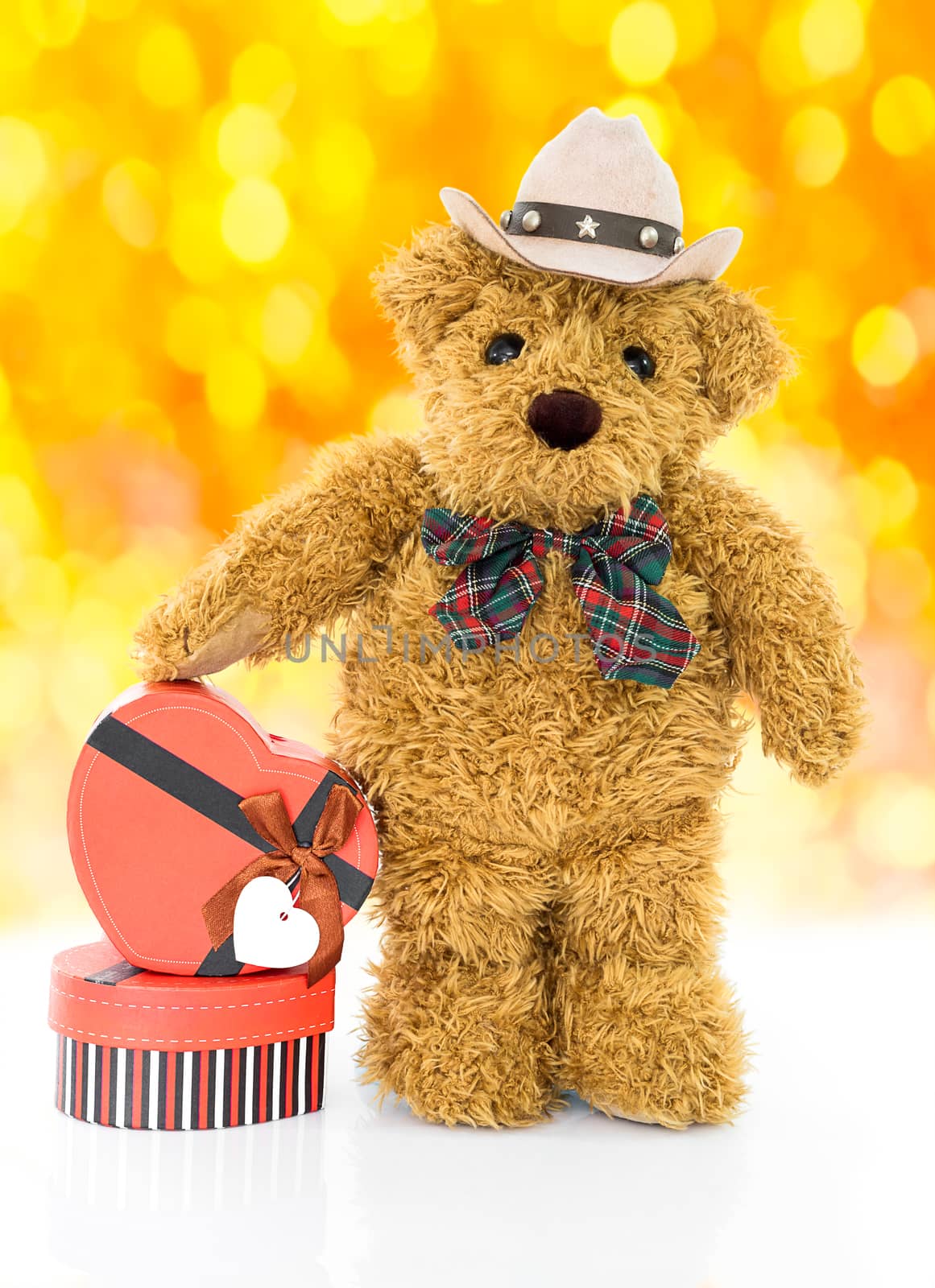 Teddy bear with 
Red heart shaped gift box on yellow bokeh background