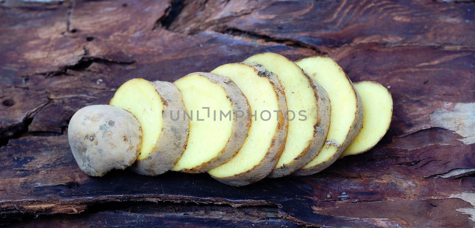 Sliced potatoes on dark wood background by nehru