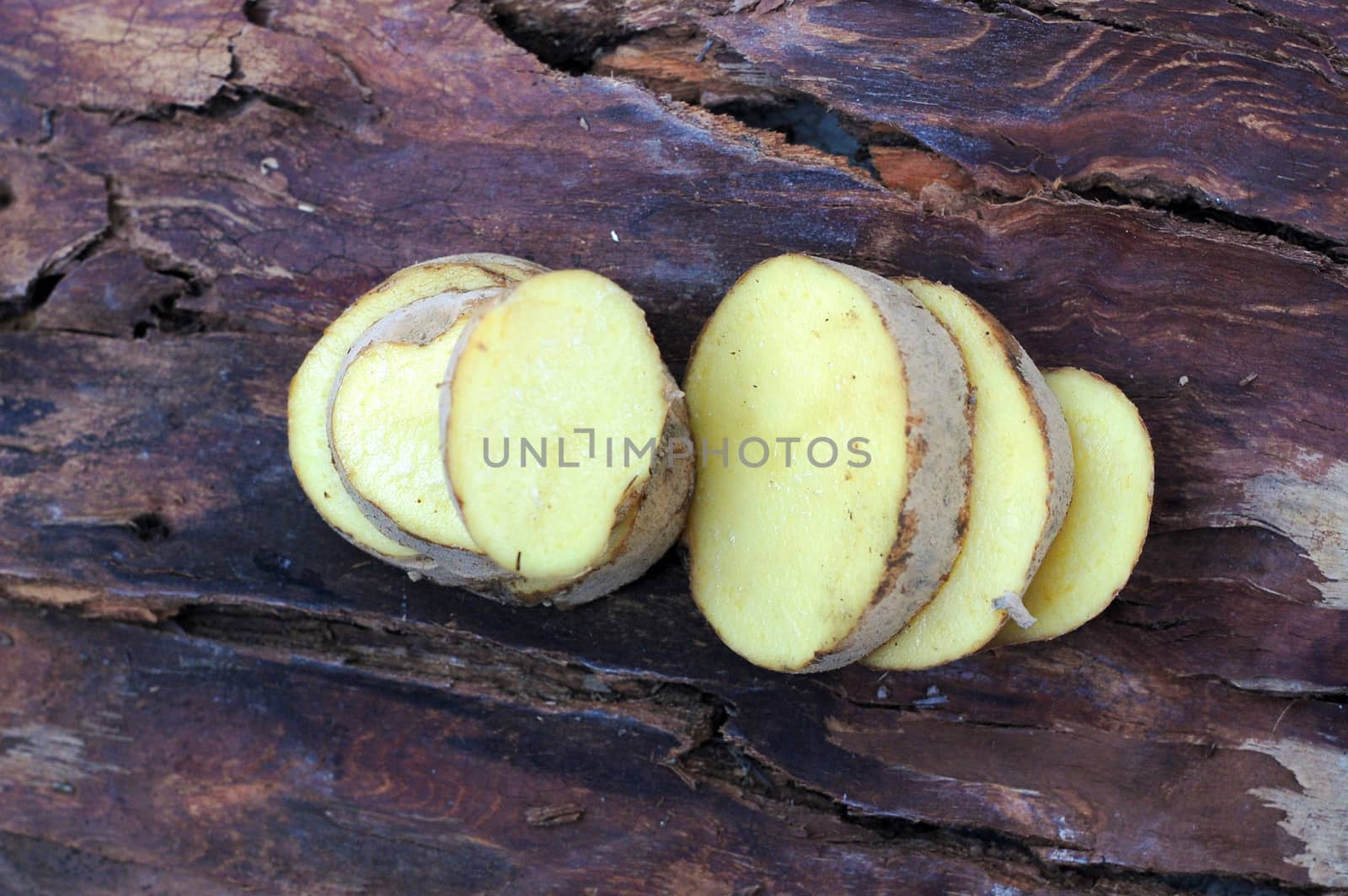 Sliced potatoes on dark wood background by nehru