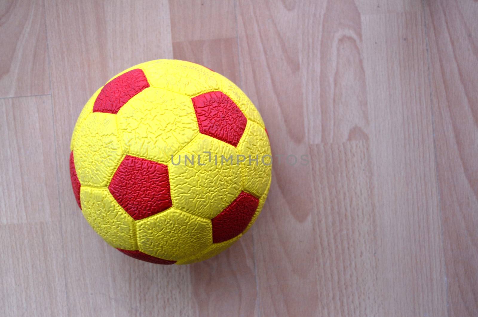 Red and yellow Soccer Ball on a wood by nehru