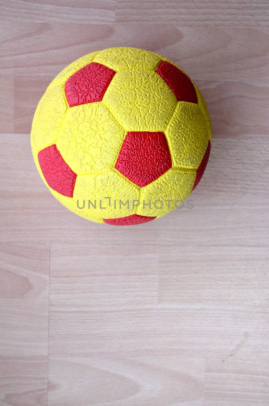 Red and yellow Soccer Ball on a wood by nehru