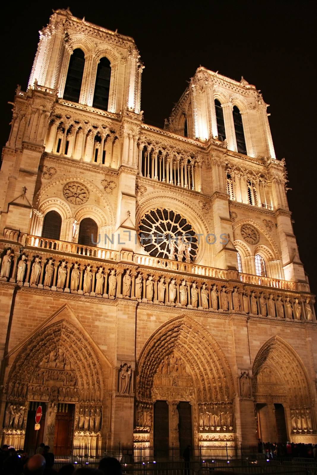 Paris, France - December 25, 2005: Evening in Paris, and the lights on Paris's iconic Cathederale de Notre Dame come on, illuminating the grand structure's gothic features. Numerous tourists are blurred by the long exposure.