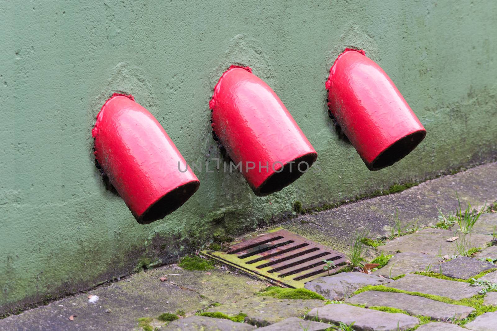 Rainwater drain. Old red gutter downpipe with weathered dirty metal frame.