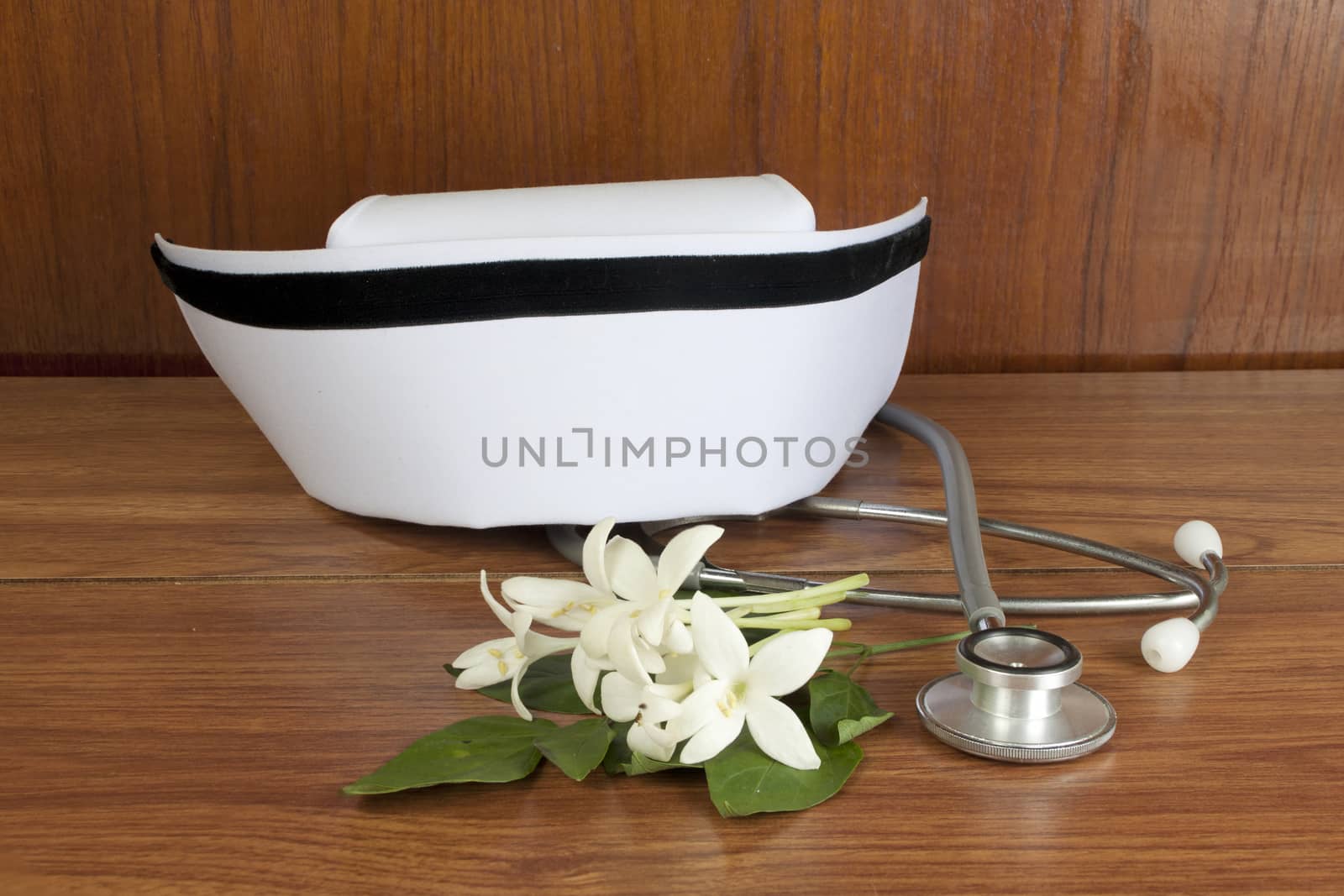 Hat nurse white and Millingtonia hortensis flowers and stethoscope on wood table. symbol of nursing thailand and Thai traditional medicine.