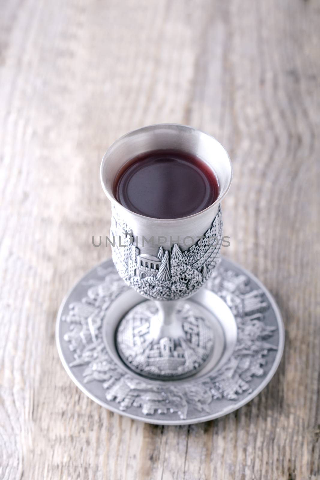 Silver kiddush cup with wine on the wooden table 