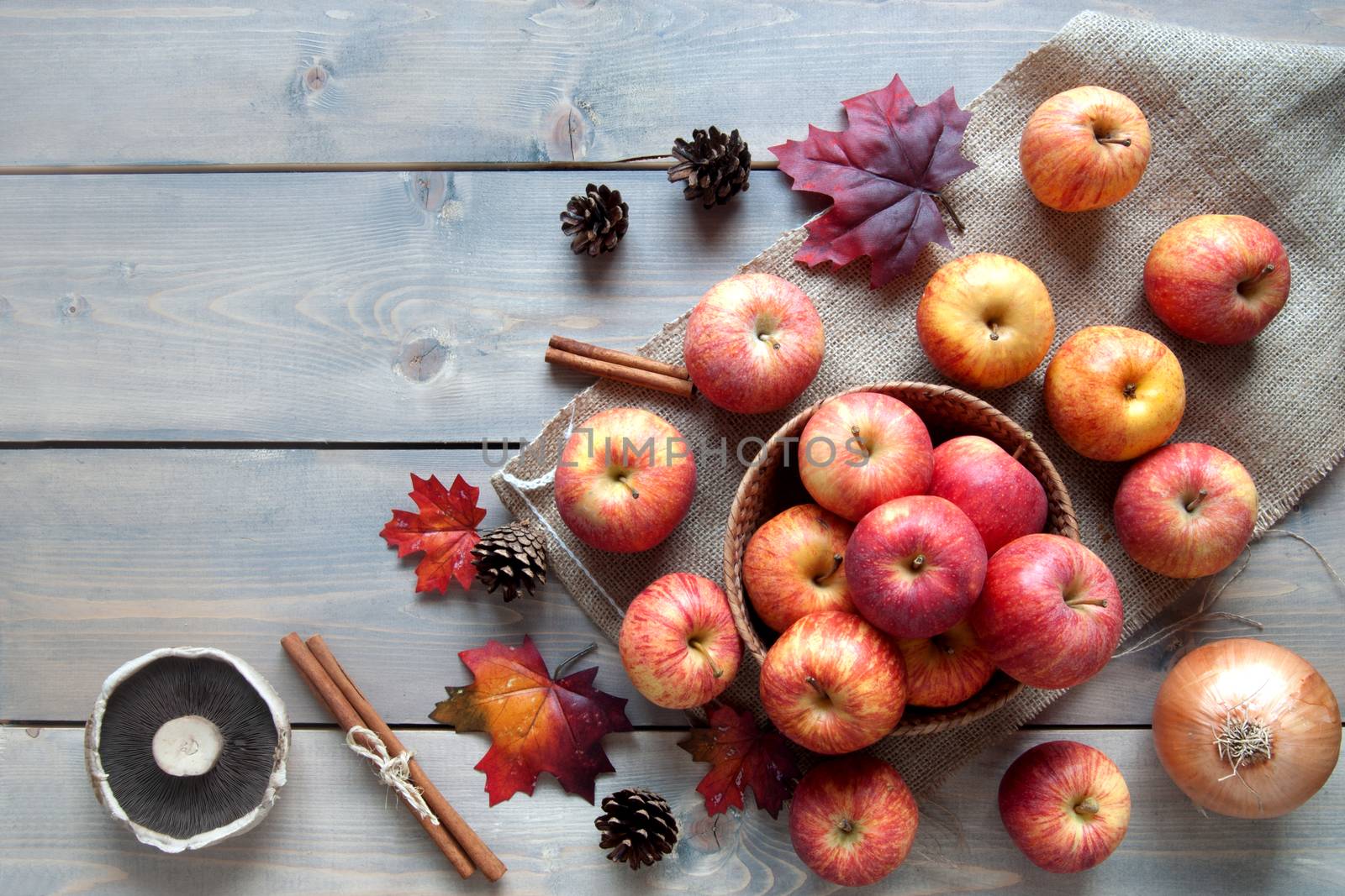 Autumn leaves, apples over a wooden background with space 