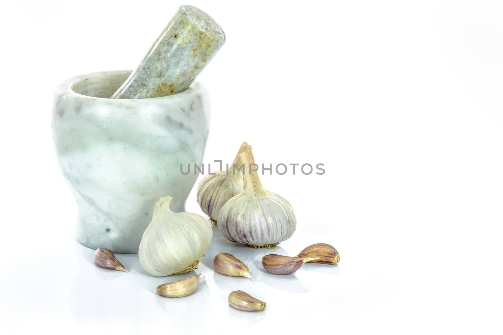 Garlic bulbs and cloves with marble mortar and pestle isolated on a white background.