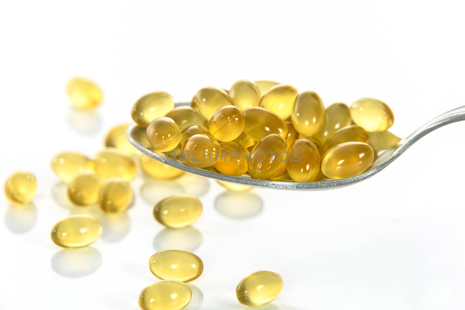 Yellow and transparent capsules on a spoon and scattered on the table