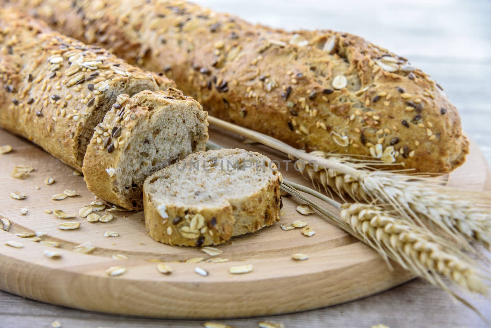 Rich in fiber dark bread on a wooden board with ears of corn of rye