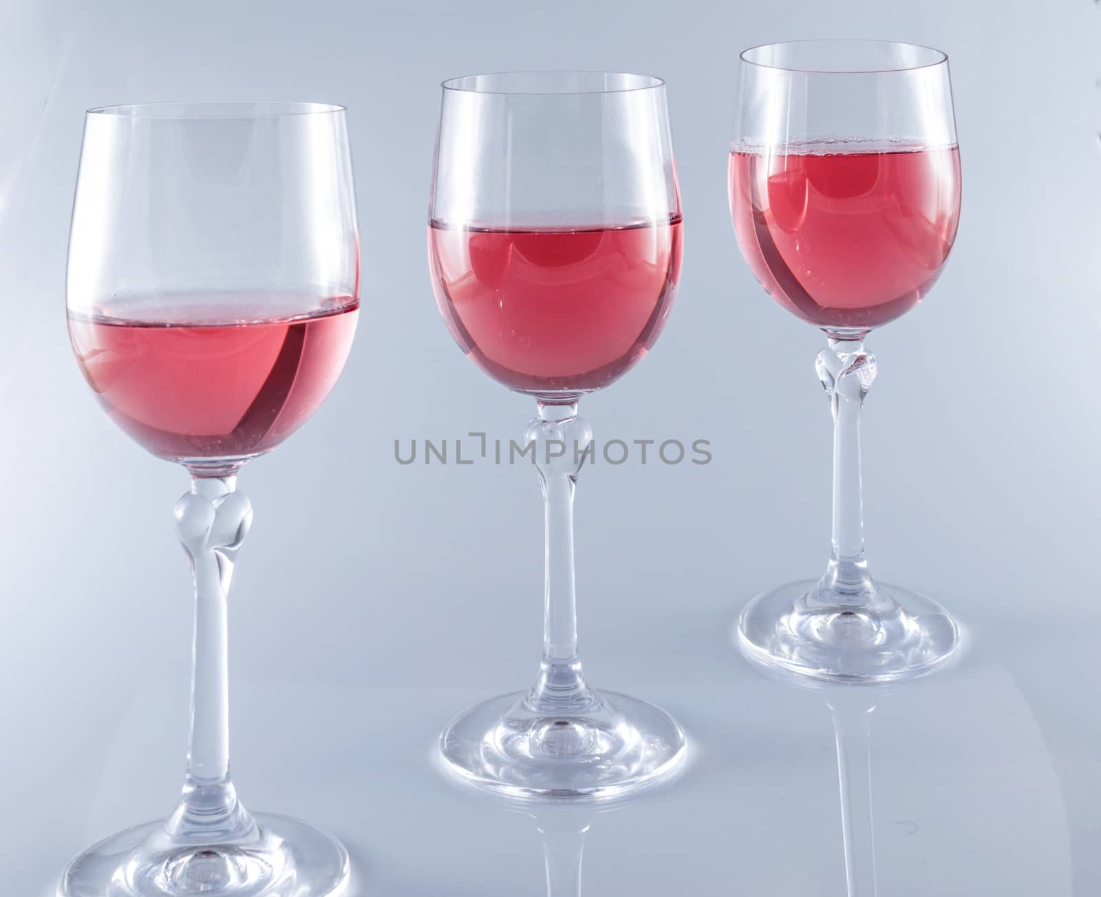 Pink wine in stemmed glasses on white background by replica