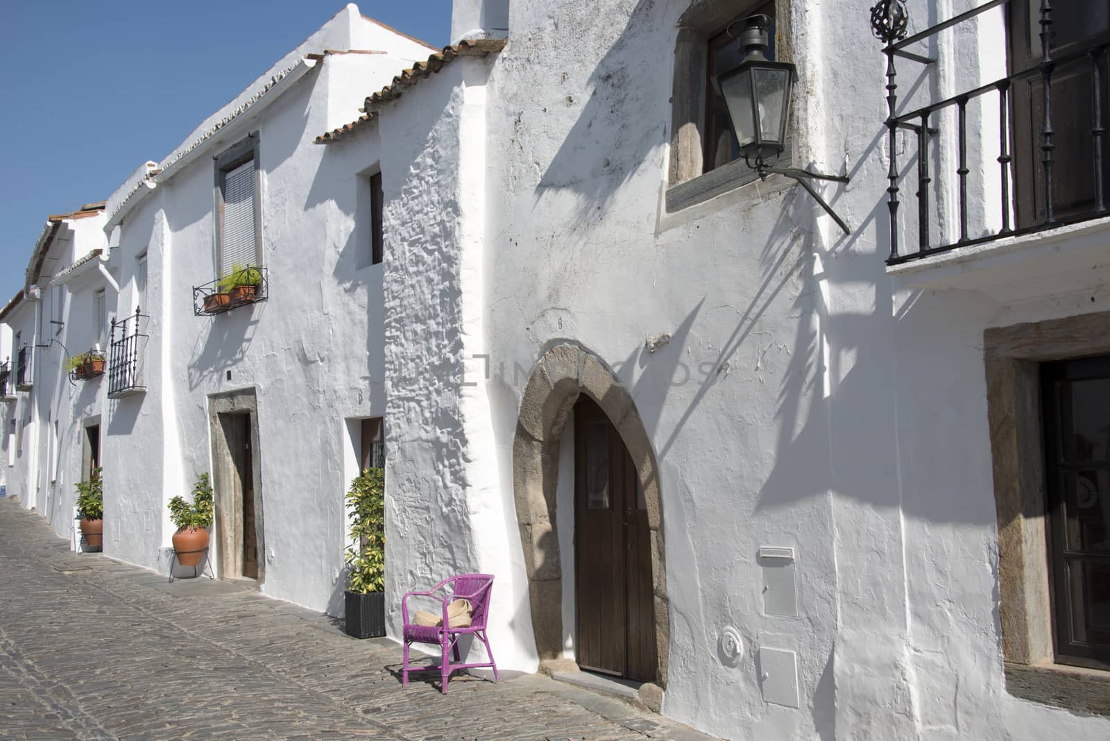 typical street in monsaraz with white houses and pink chair anf flowers in the town
