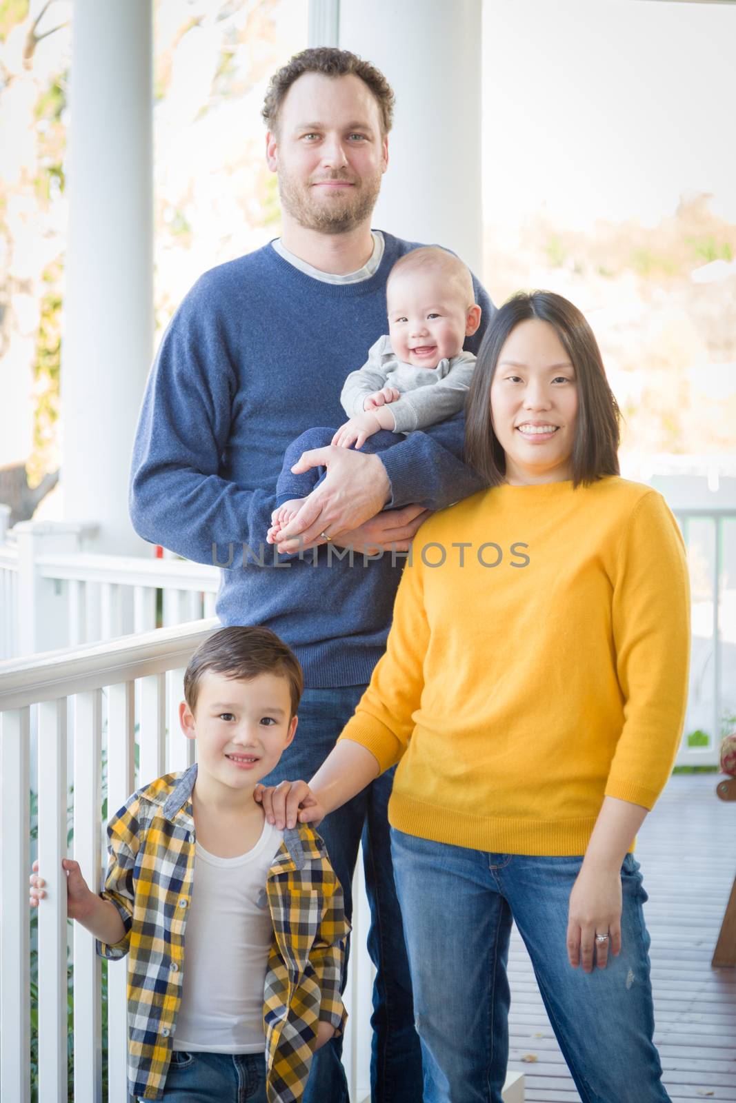Young Mixed Race Chinese and Caucasian Family Portrait On Their Front Porch.