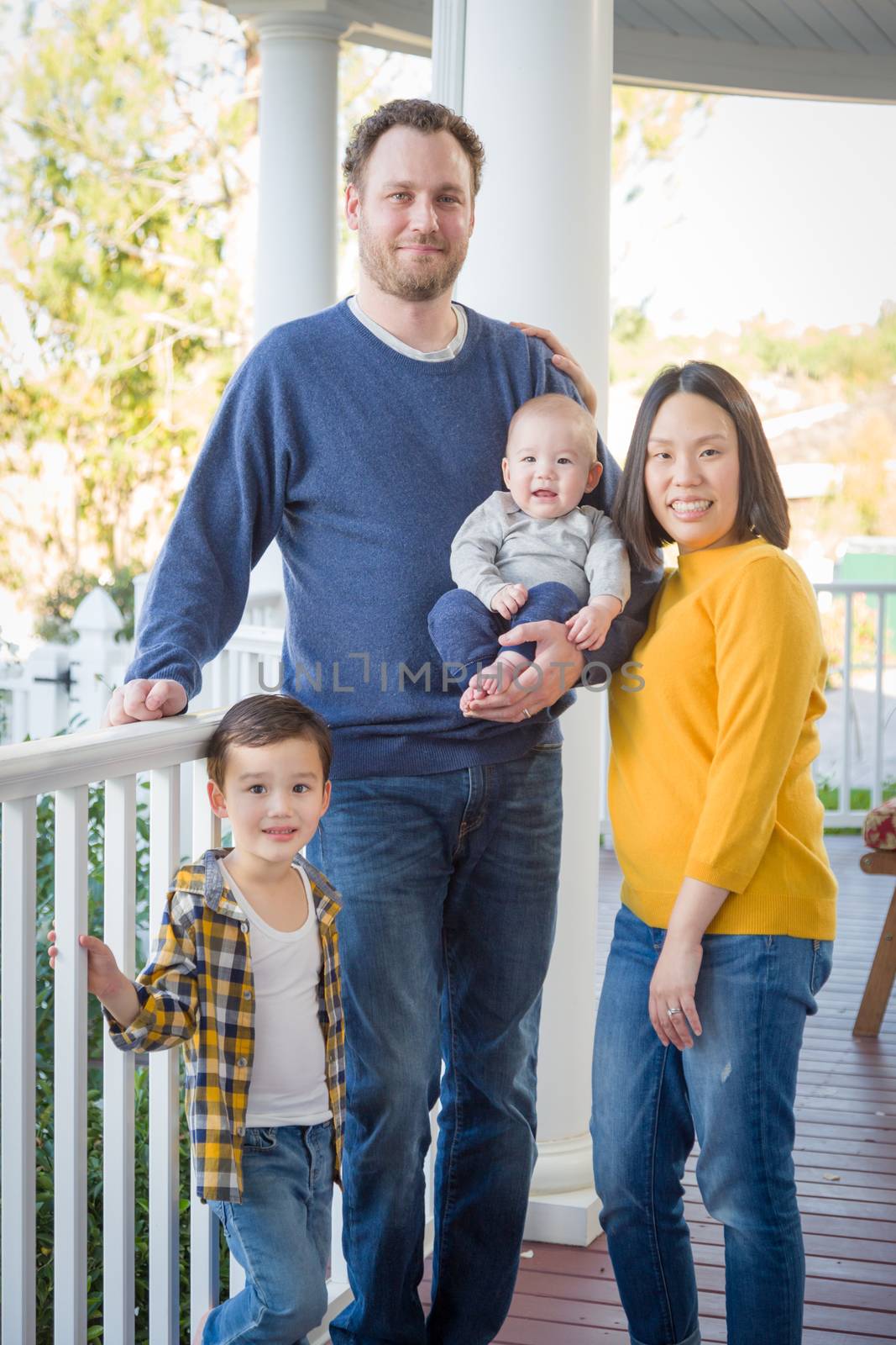 Young Mixed Race Chinese and Caucasian Family Portrait On Their Front Porch.