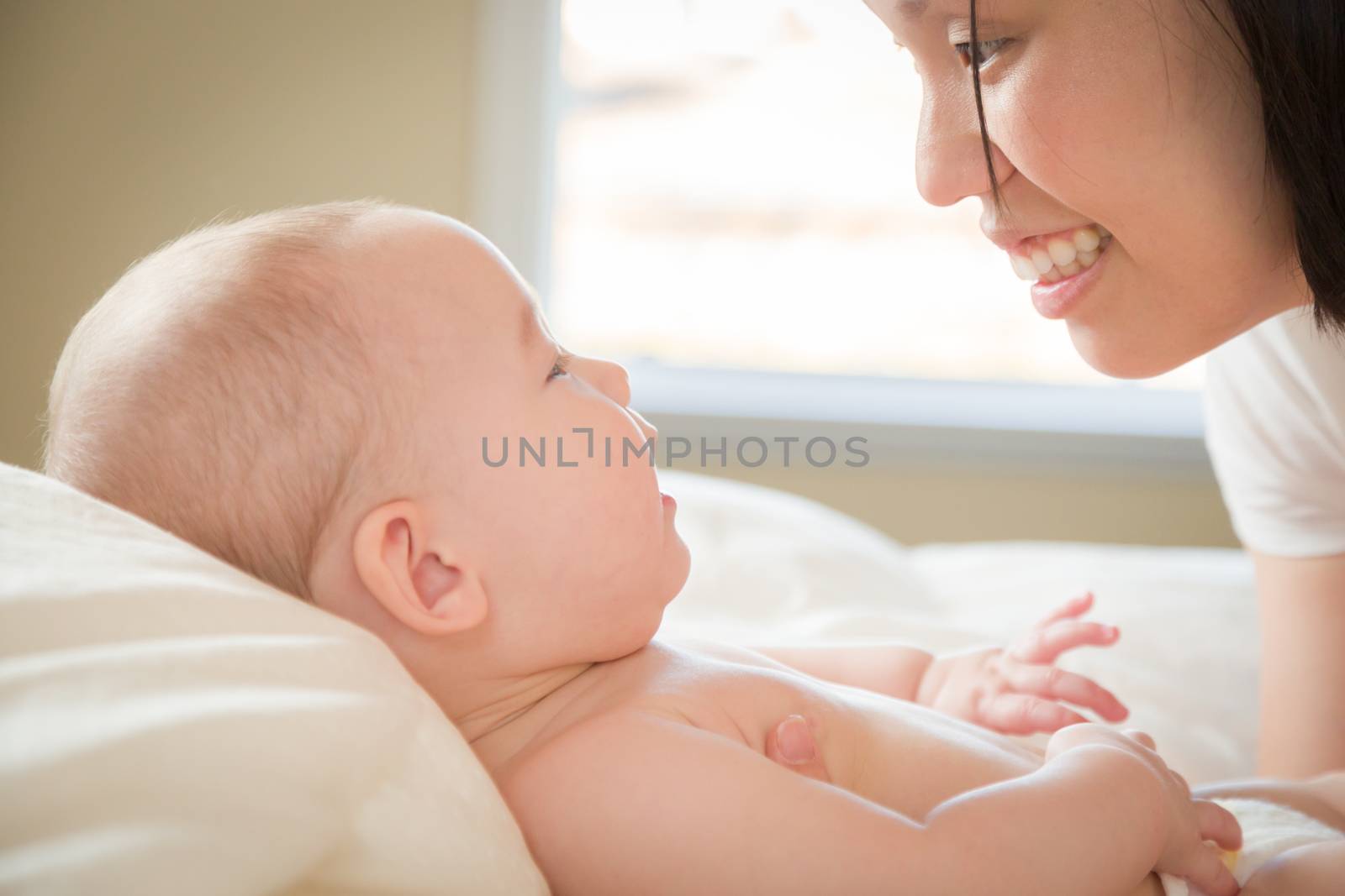 Young Mixed Race Chinese and Caucasian Baby Boy Laying In His Bed with His Mother.