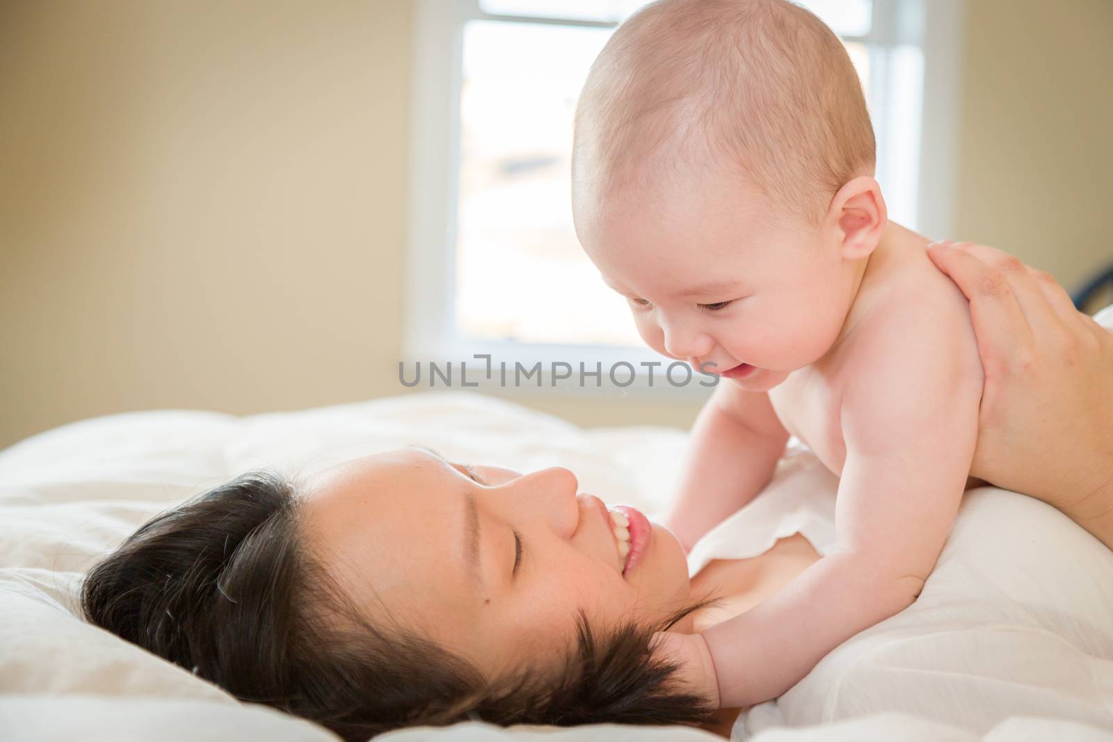 Young Mixed Race Chinese and Caucasian Baby Boy Laying In His Bed with His Mother.