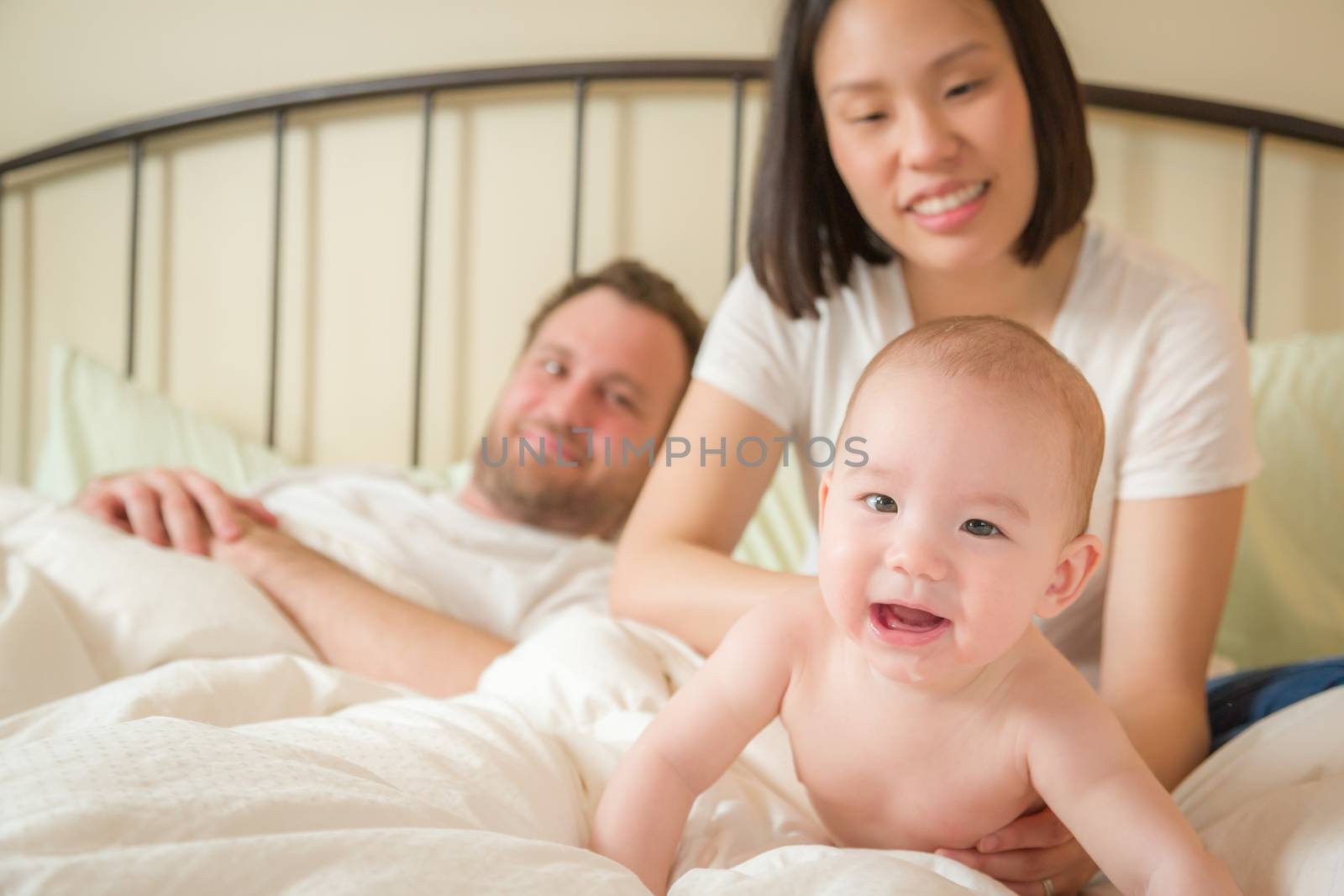 Chinese and Caucasian Baby Boy Laying In Bed with His Parents by Feverpitched