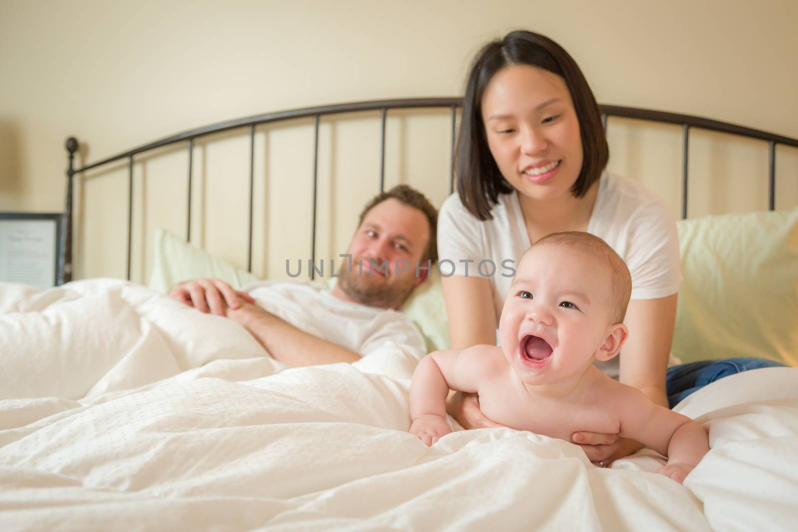 Chinese and Caucasian Baby Boy Laying In Bed with His Parents by Feverpitched
