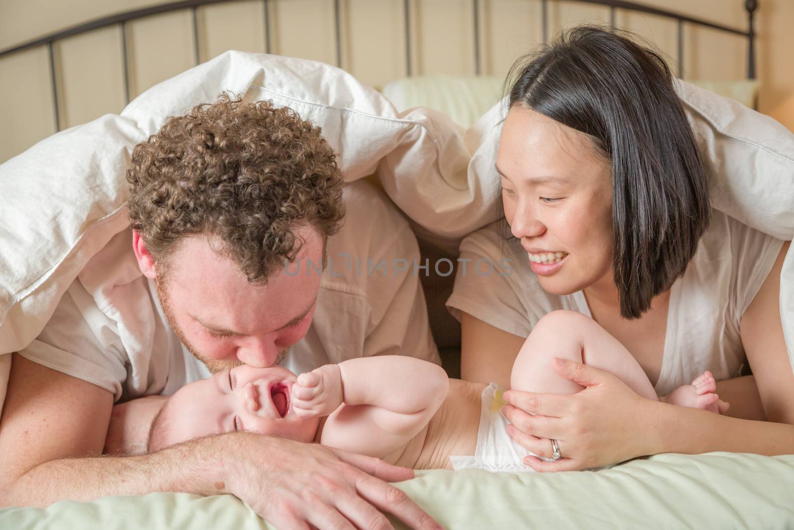Mixed Race Chinese and Caucasian Baby Boy Laying In Bed with His Father and Mother.
