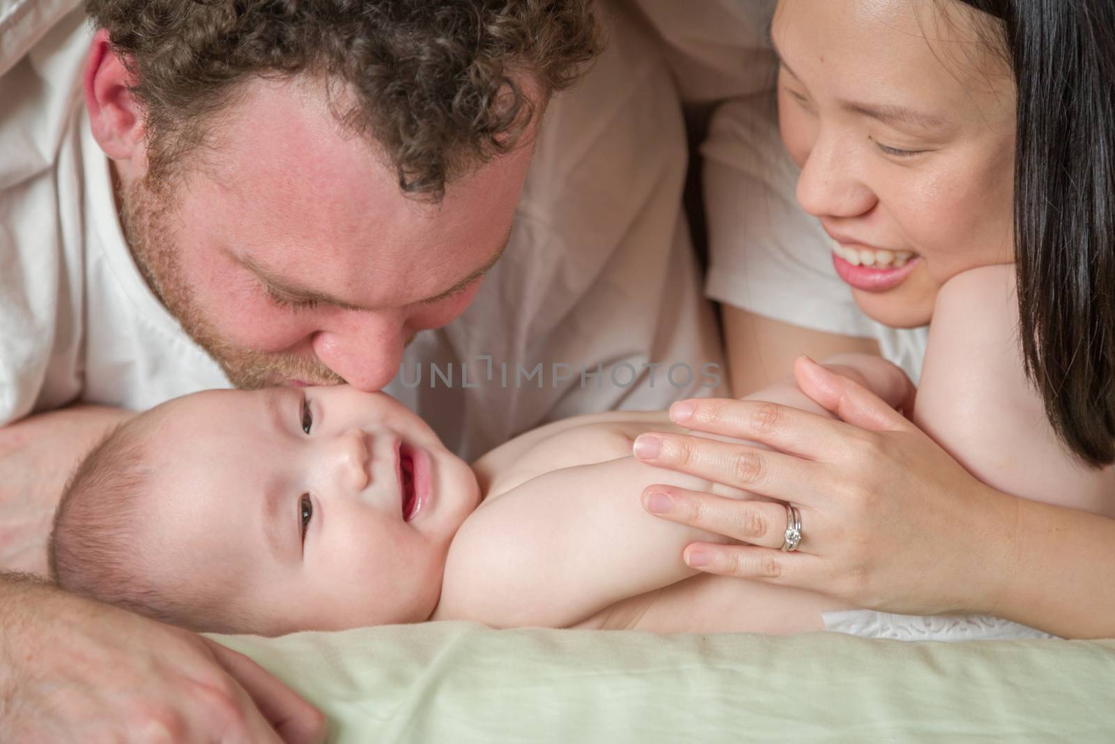 Mixed Race Chinese and Caucasian Baby Boy Laying In Bed with His Father and Mother.