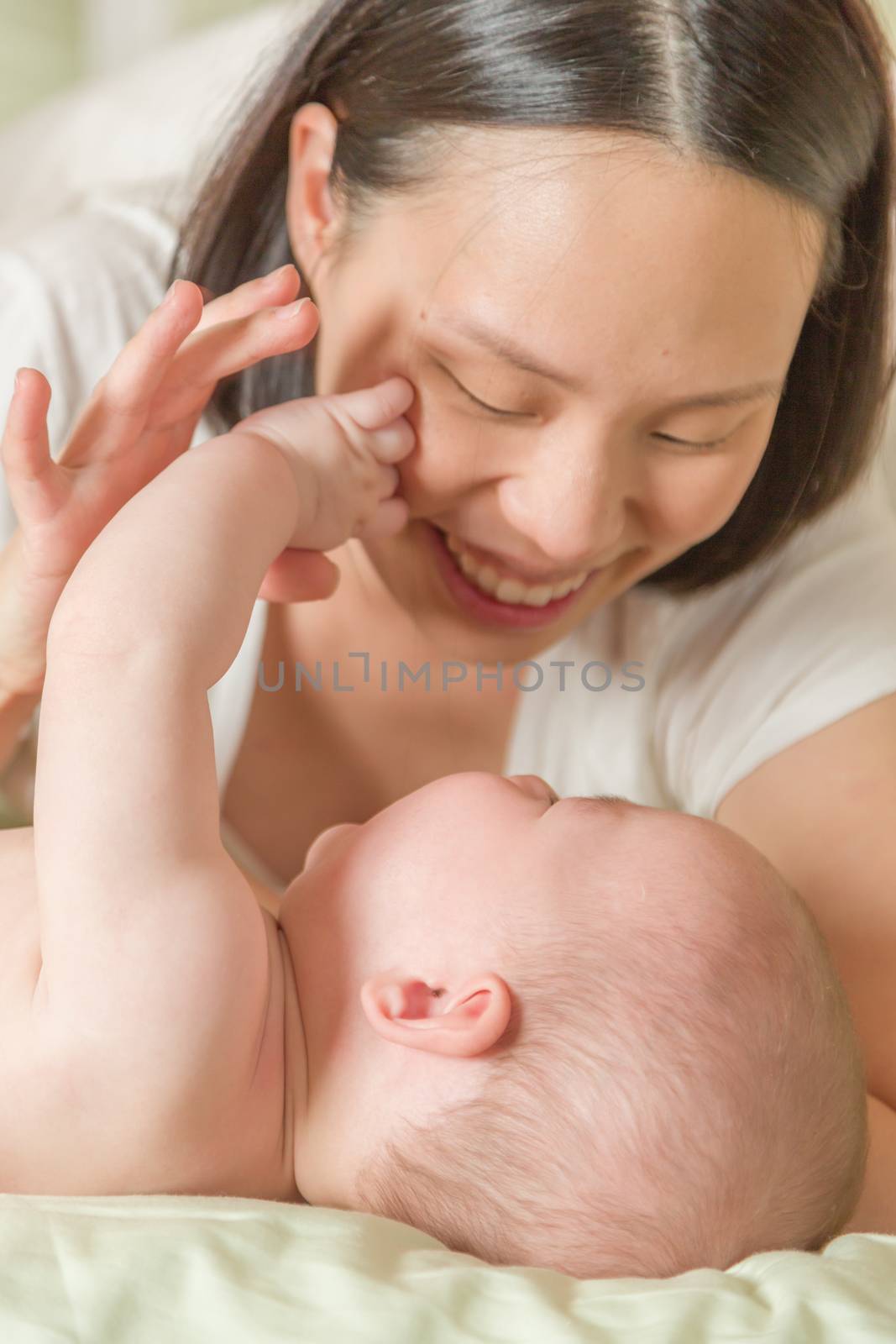 Mixed Race Chinese and Caucasian Baby Boy Laying In Bed with His Mother.