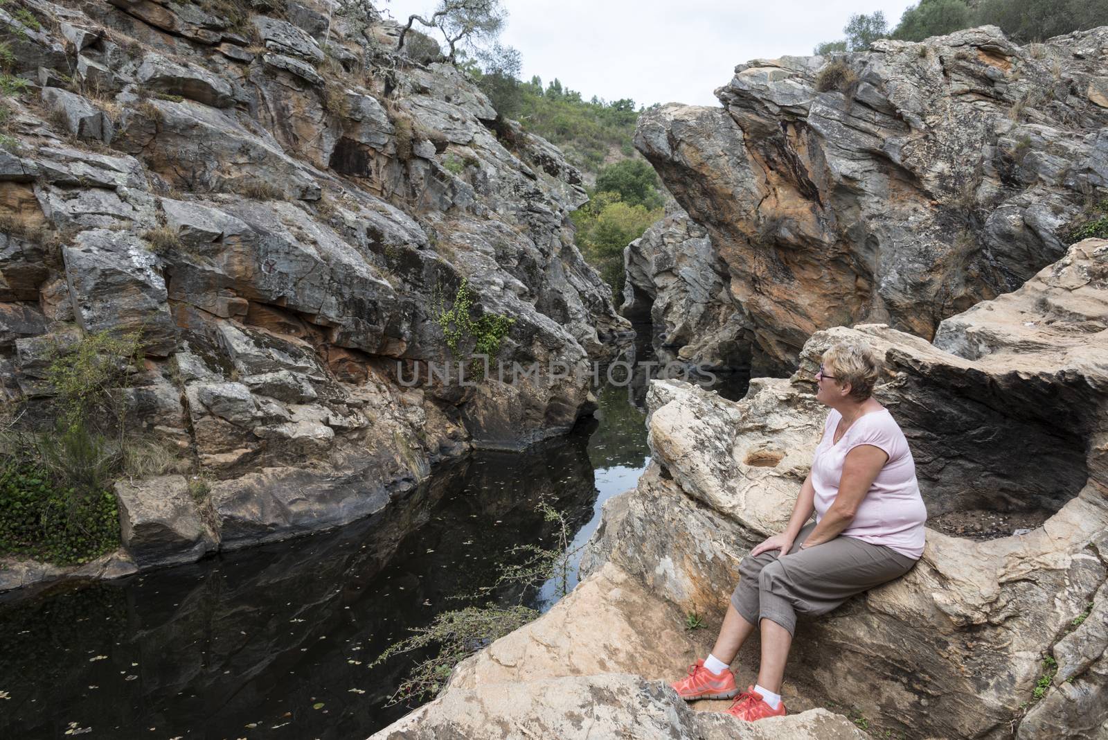 woman looking at the rocks at small river with pond in nature portugal near odemira called pego des pias