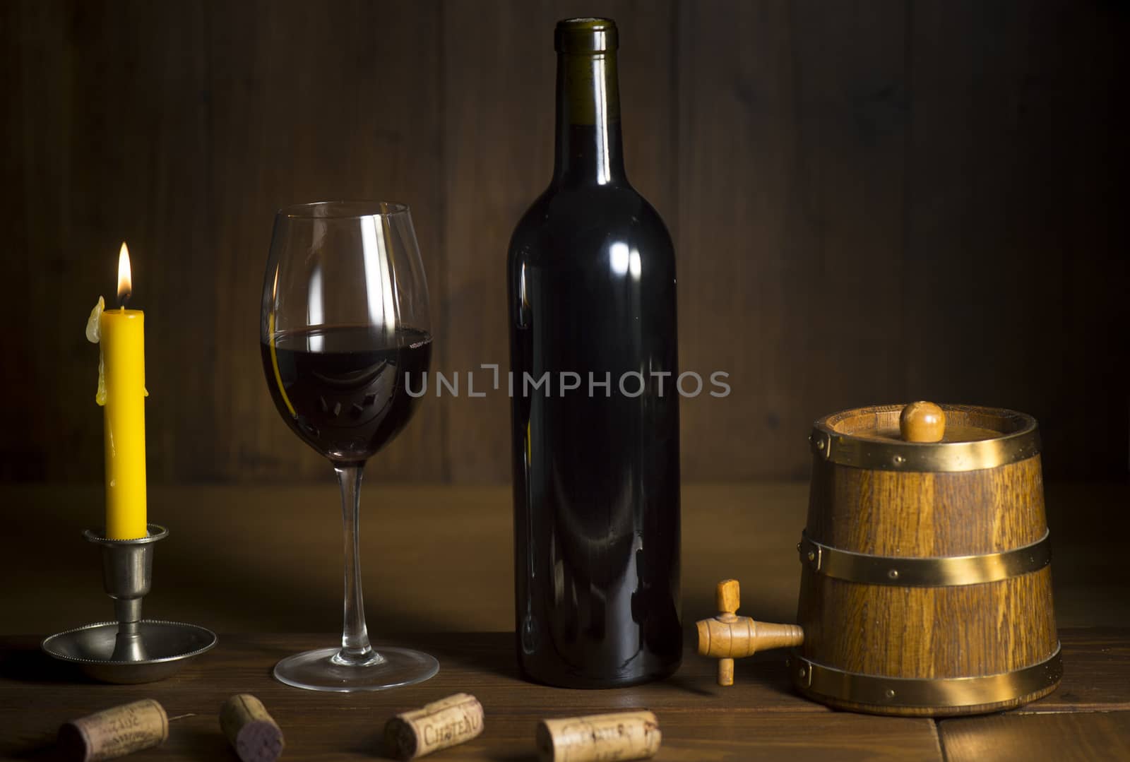 Pouring red wine into wineglass from green bottle, brown background
