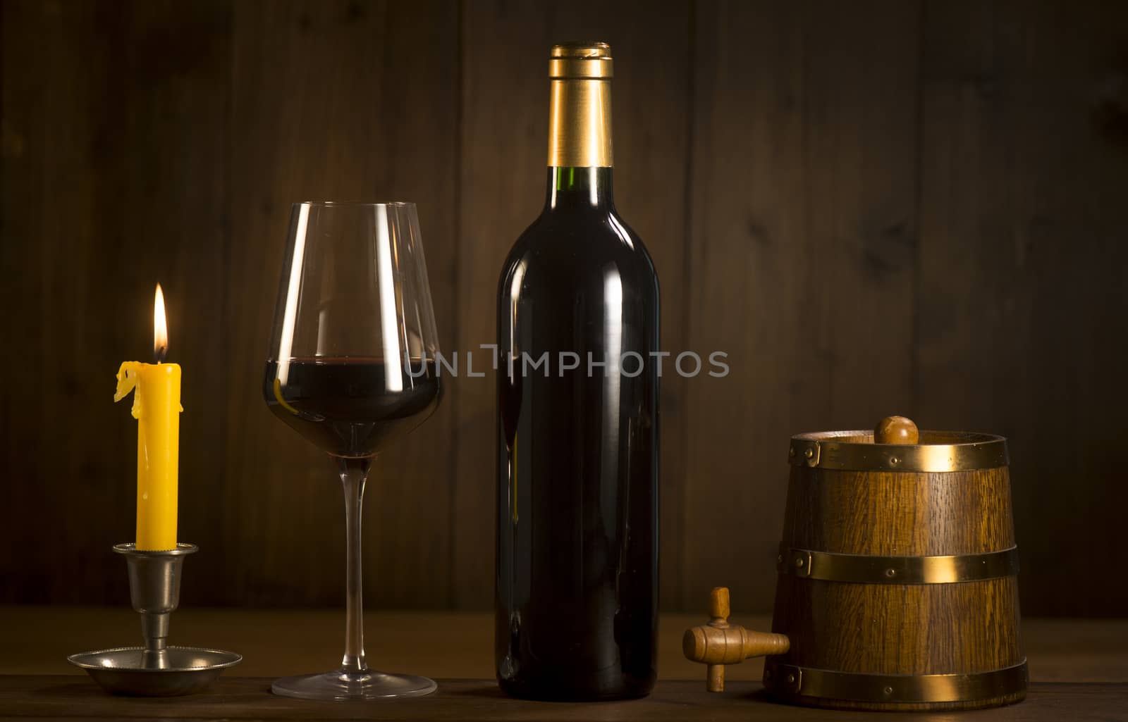 Pouring red wine into wineglass from green bottle, brown background