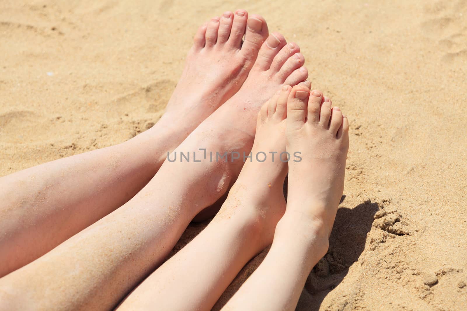 Feet of mother and her child in the sand