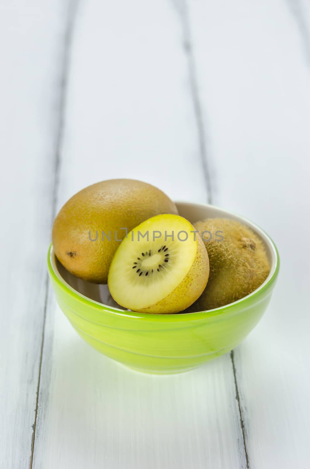 Kiwi fruit in a bowl on wooden background