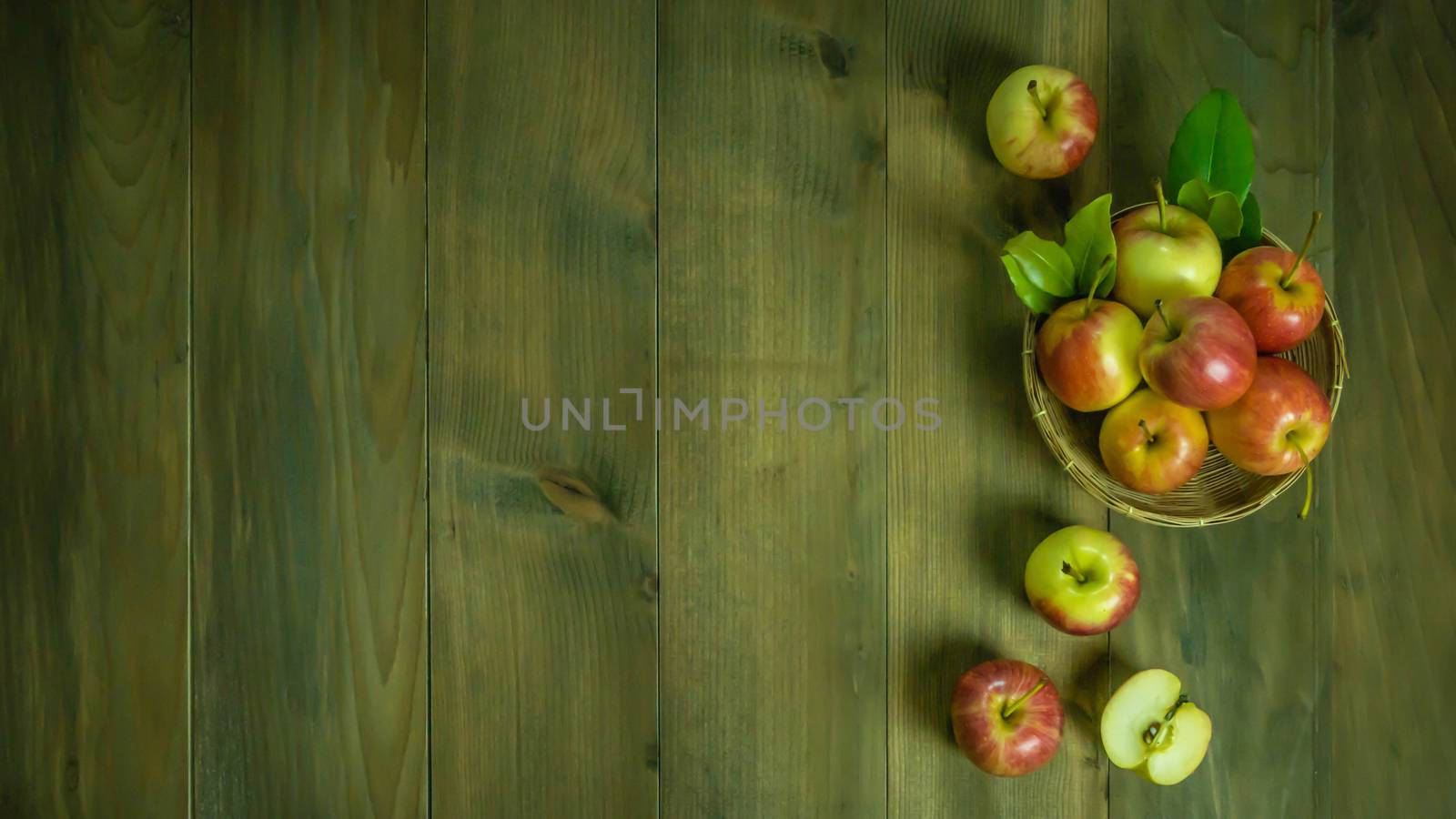 Top view red and yellow apple with leaves and  bamboo basket on wooden background with free space for text