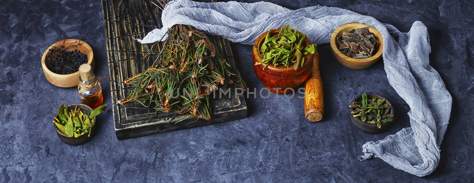 Bundle herbs and mortar with pestle on slate background.Copy space