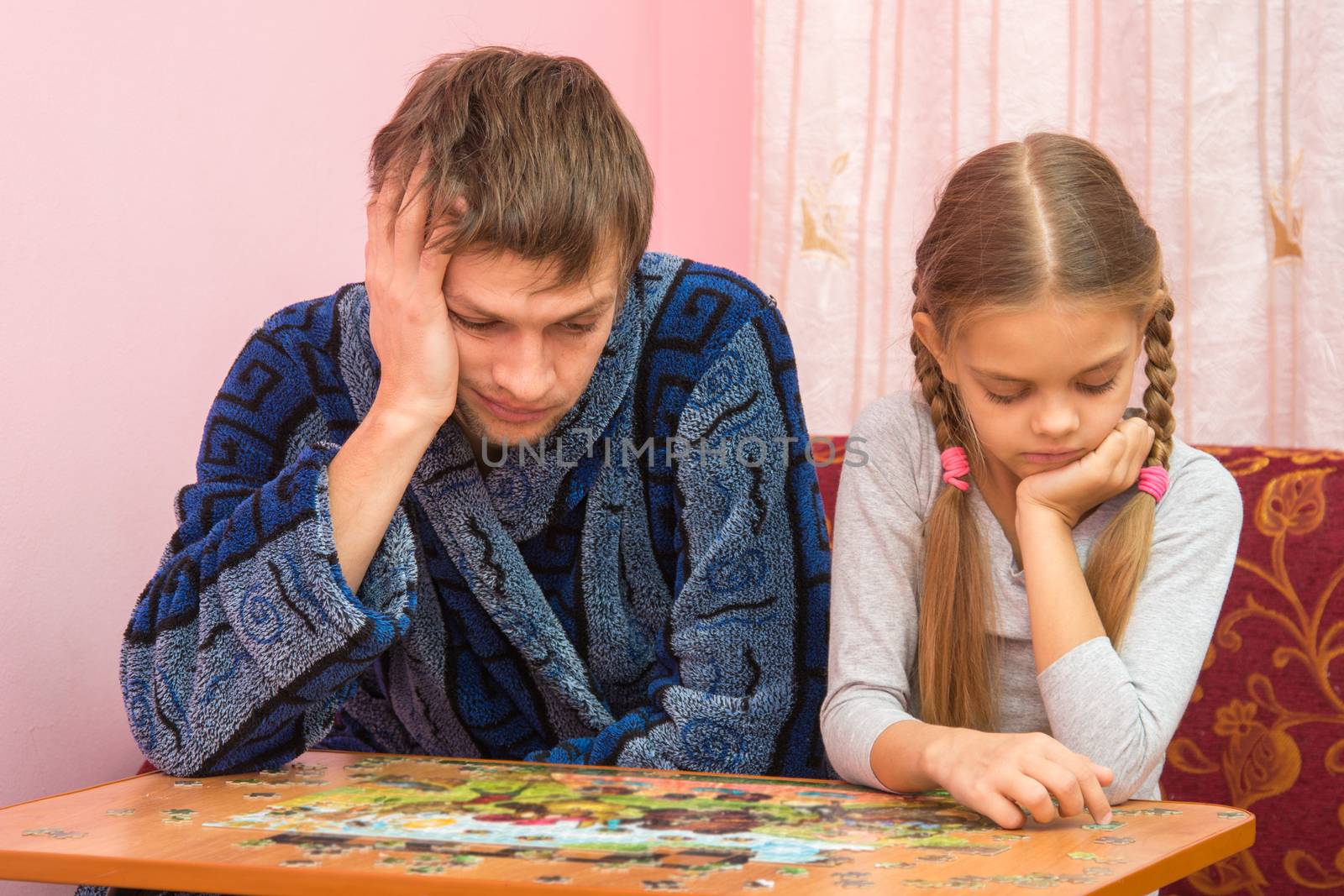 My daughter collects a picture from puzzles, tired dad sitting next by Madhourse