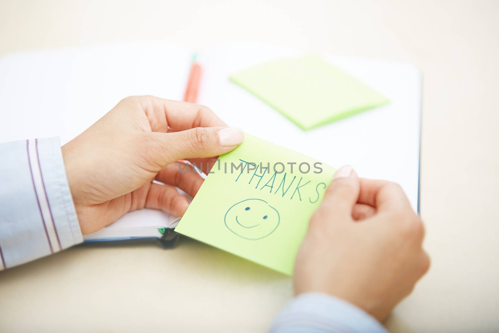 Hands of woman holding sticky note with Thanks text