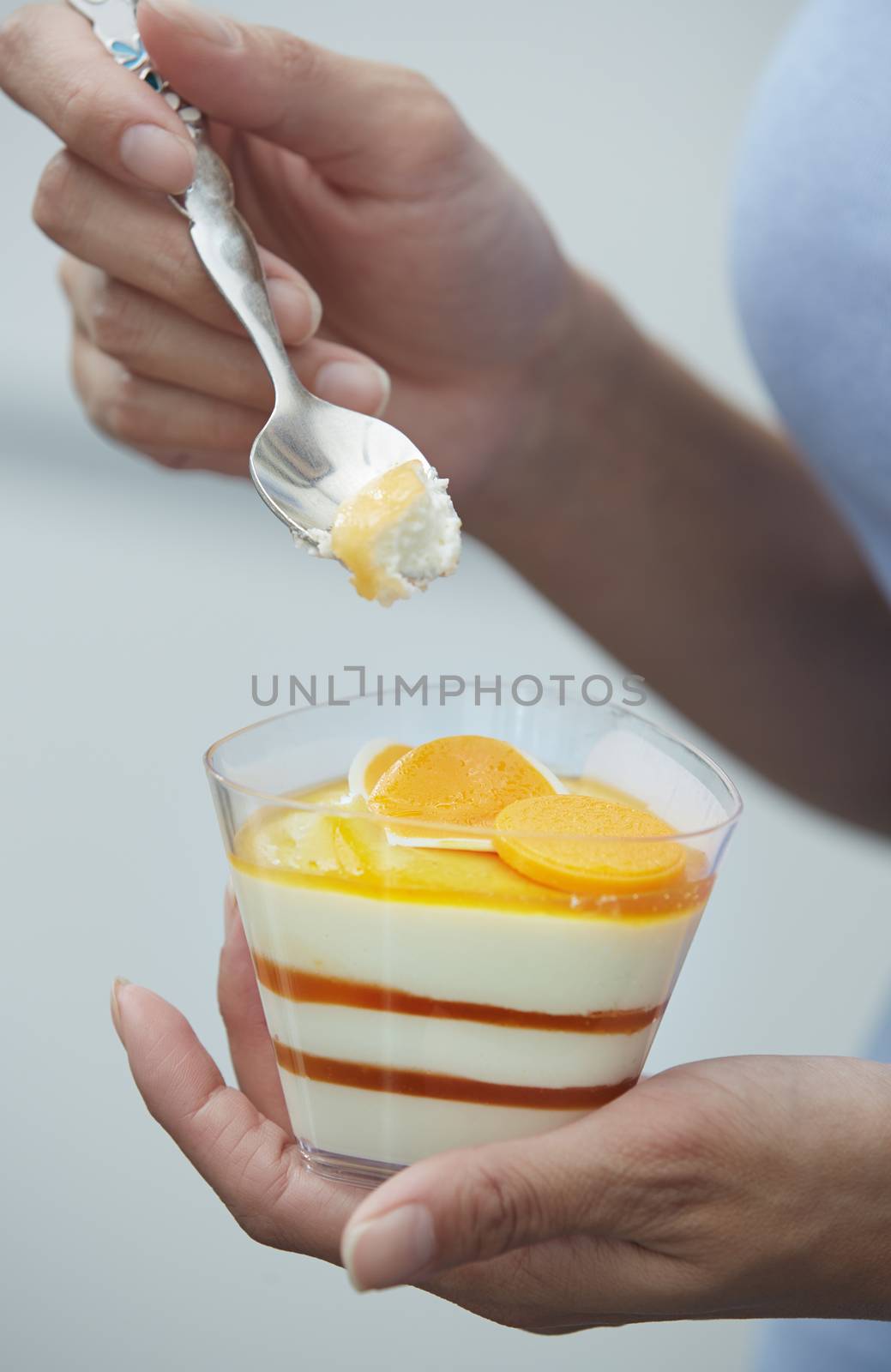 Hands of woman eating fruit mousse