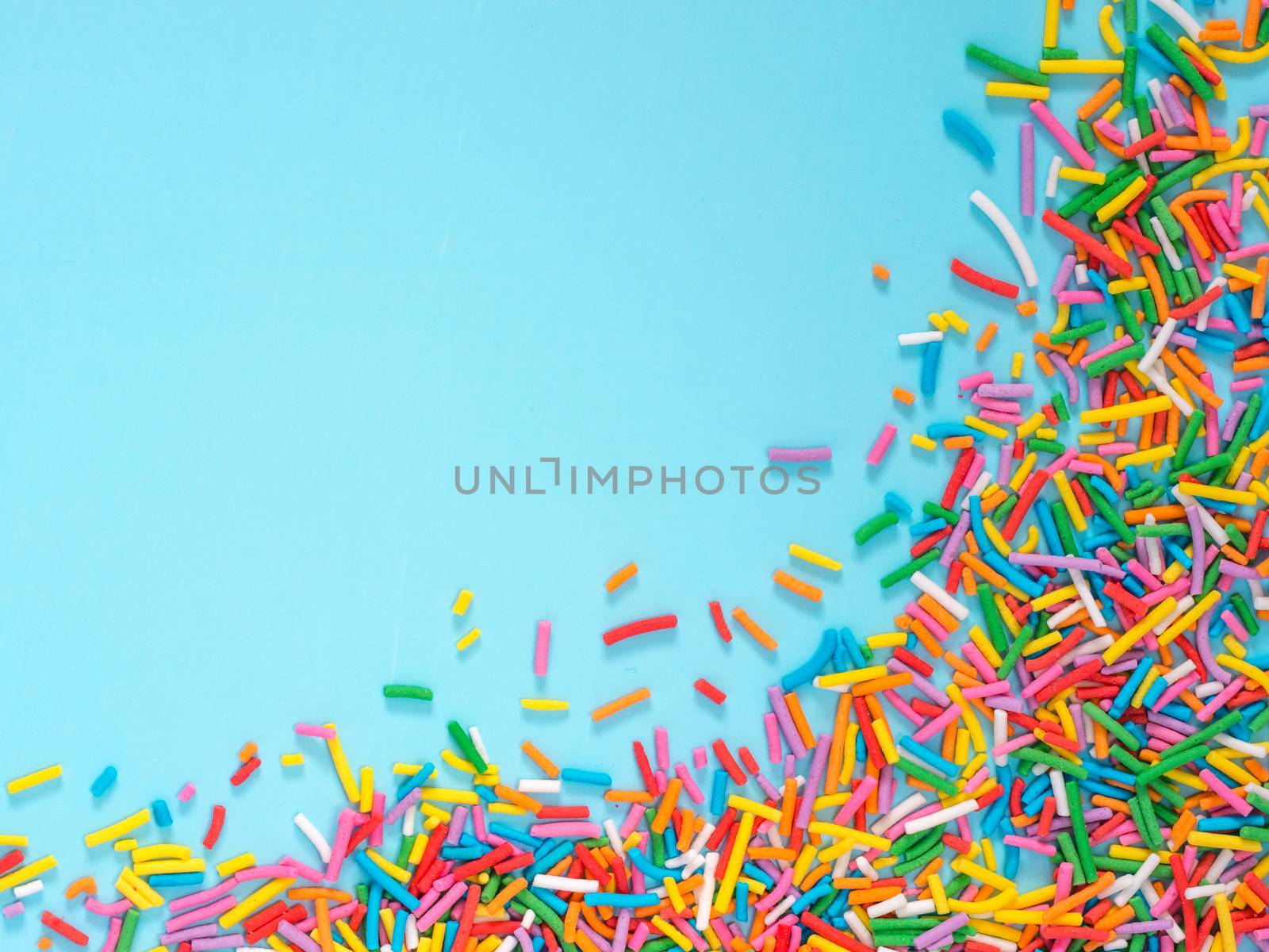 Border frame of colorful sprinkles on blue background by fascinadora