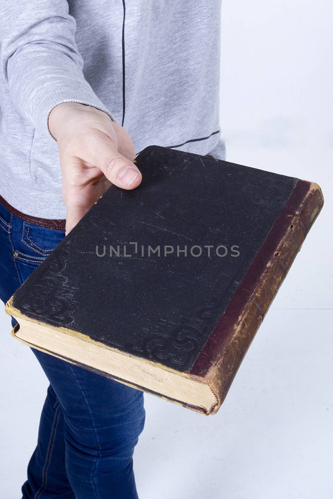 Female hand holding an old book on a white background
