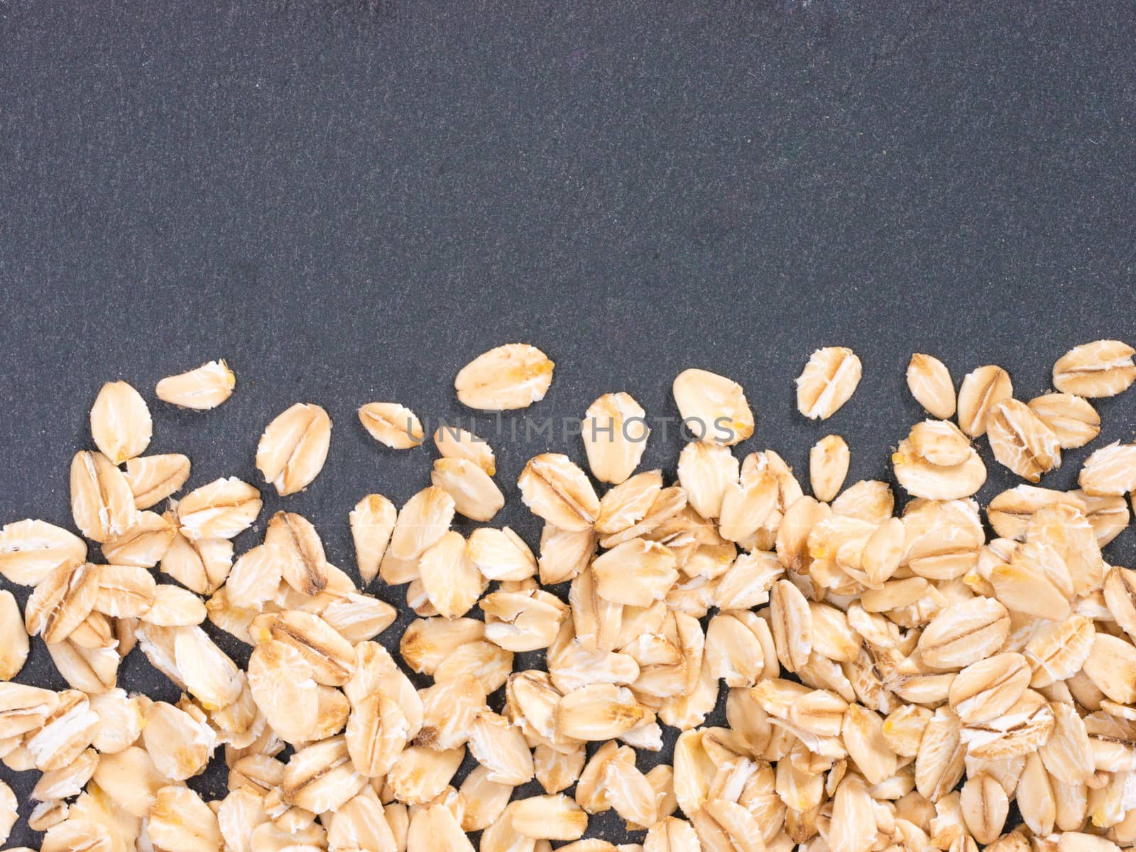 raw oatmeal on gray background with copy space. Isolated one edge. Top view or flat lay.