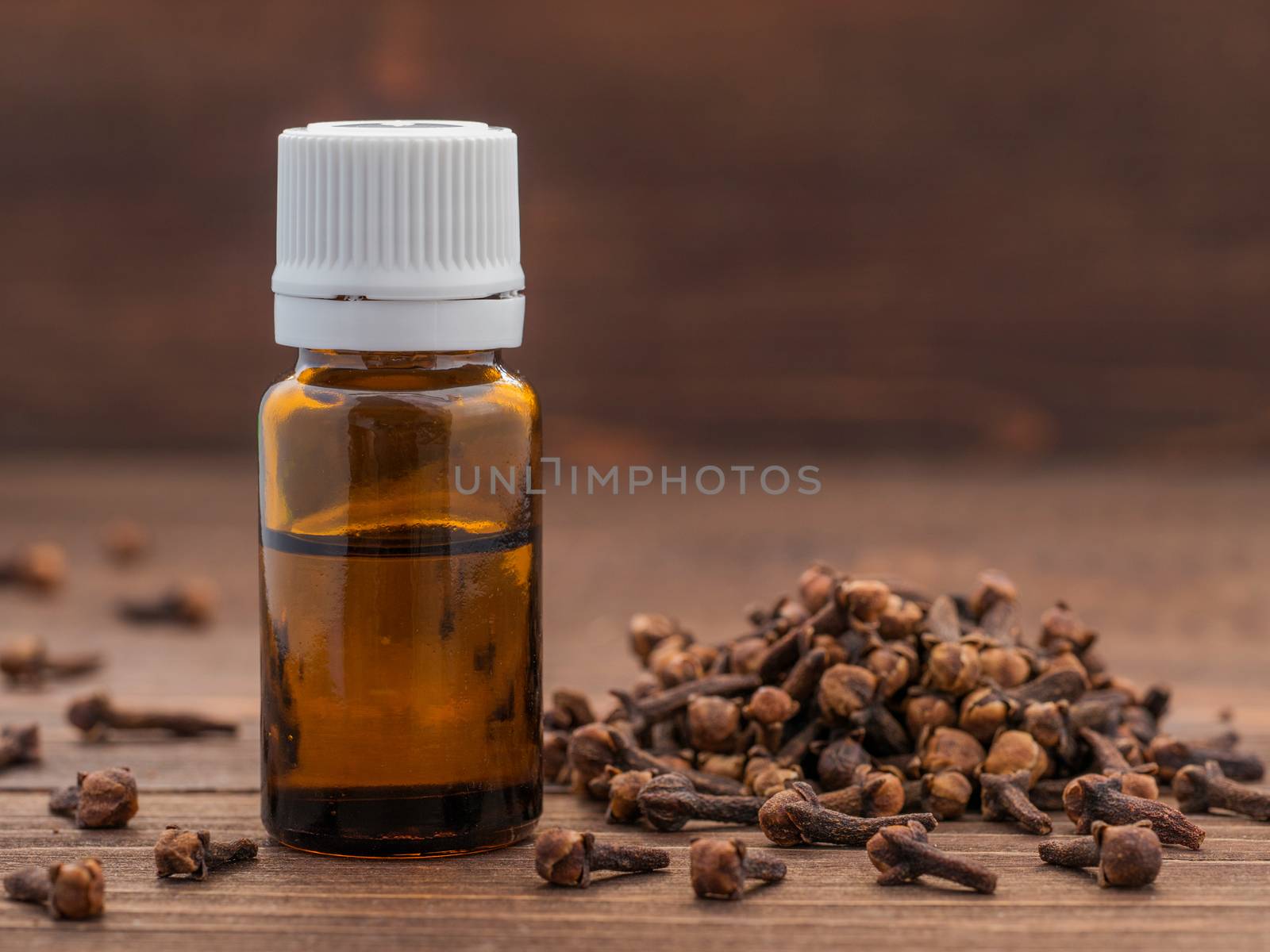 Spice clove essential oil in dark glass bottle anddry cloves on dark wooden background with copy space