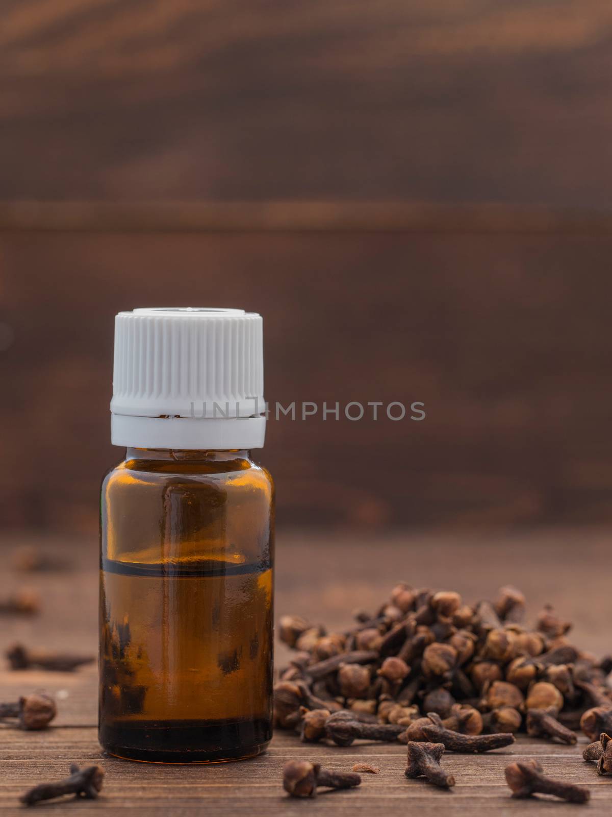 Spice clove essential oil in dark glass bottle anddry cloves on dark wooden background with copy space