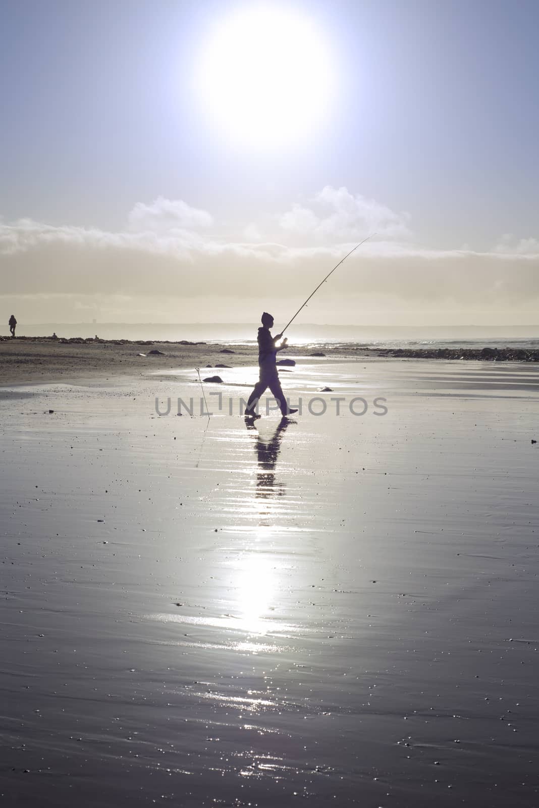 lone fisherman fishing on the sunny Kerry beach by morrbyte