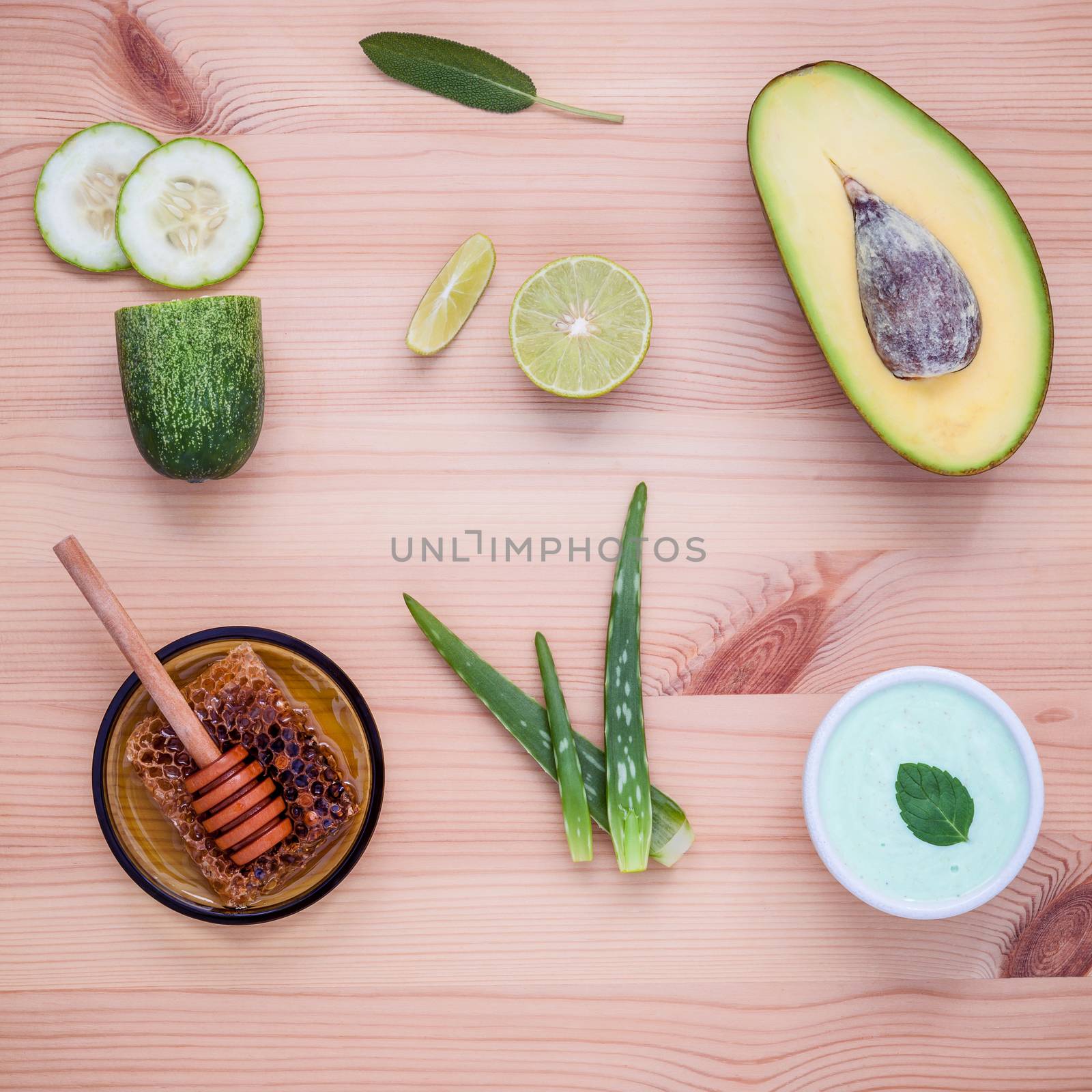 Homemade skincare and body scrubs with natural ingredients avocado ,aloe vera ,lemon ,cucumber sliced ,sea salt ,peppermint leaves ,sage leaves ,avocado scrubs and honey set up on wooden background.