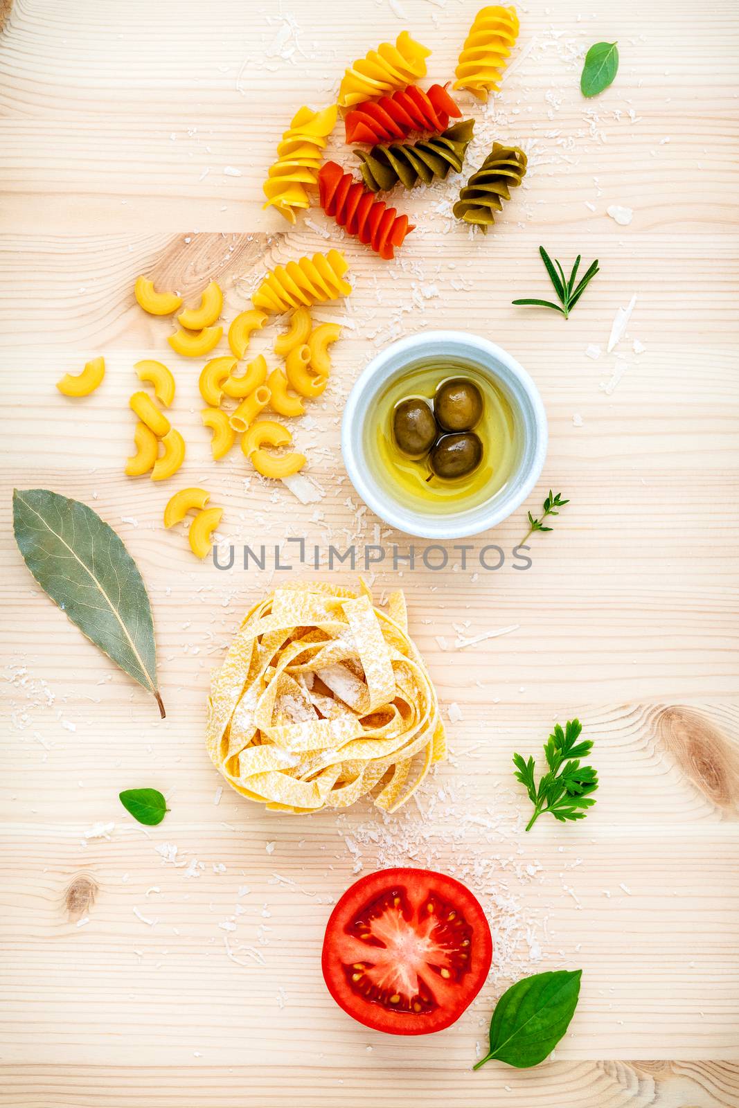 Italian food concept various kind of pasta with olive oil flavored and spices herbs rosemary ,thyme ,parsley ,oregano ,bay leaves ,tomato and parmesan cheese  flat lay on wooden background.